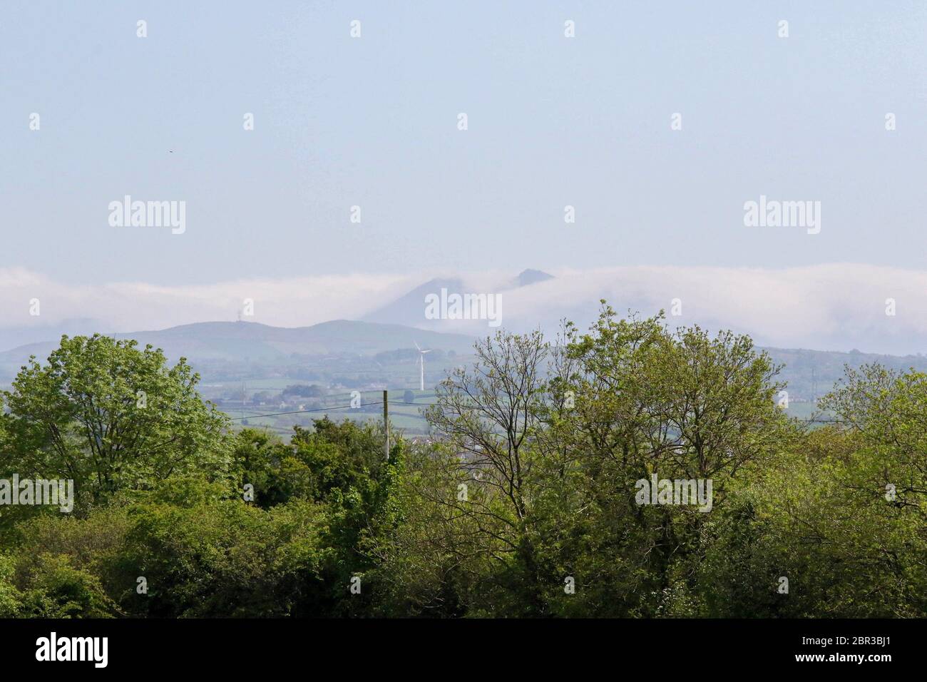 Dromore, County Down, Nordirland. 20 Mai 2020. UK Wetter - ein warmer Tag mit Sonnennyperioden und einer leichten Brise, bevor starker Wind und etwas Regen am Wochenende eintreffen. Jenseits der Stadt Dromore, die Berge von Mourne, an der Küste, sind in niedrigen Wolken gehüllt. Kredit: CAZIMB/Alamy Live News. Stockfoto