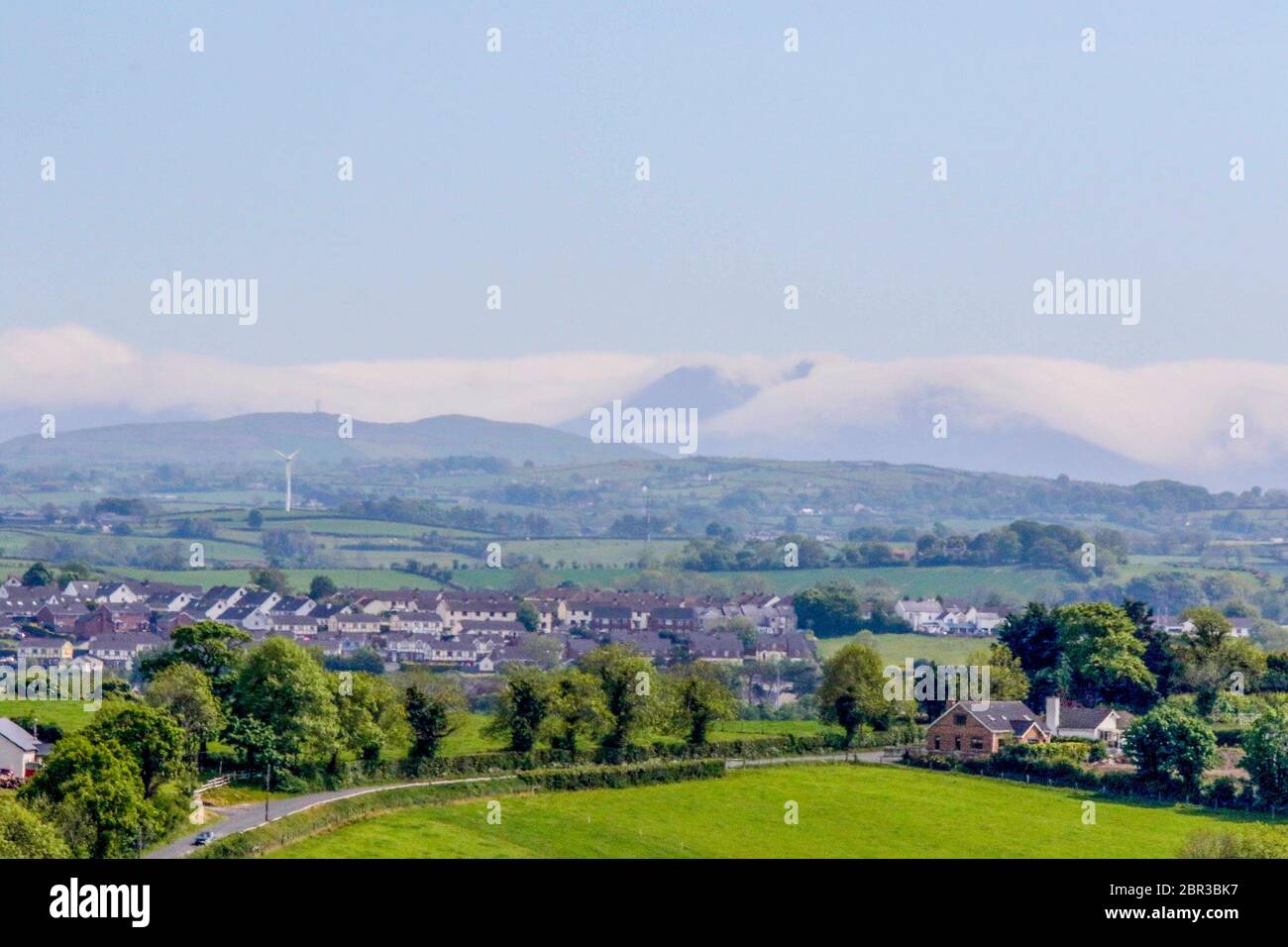 Dromore, County Down, Nordirland. 20 Mai 2020. UK Wetter - ein warmer Tag mit Sonnennyperioden und einer leichten Brise, bevor starker Wind und etwas Regen am Wochenende eintreffen. Jenseits der Stadt Dromore, die Berge von Mourne, an der Küste, sind in niedrigen Wolken gehüllt. Kredit: CAZIMB/Alamy Live News. Stockfoto