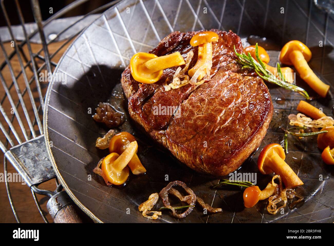 Wild Wild Wild Steak mit Waldpilzen, Zweig Rosmarin und Zwiebeln in eine Pfanne mit Vintage Spachtel serviert. Stockfoto