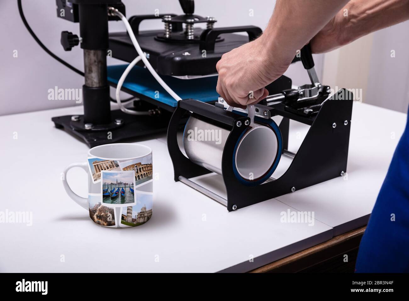 Man Druck auf Kaffeetassen in Werkstatt Stockfoto
