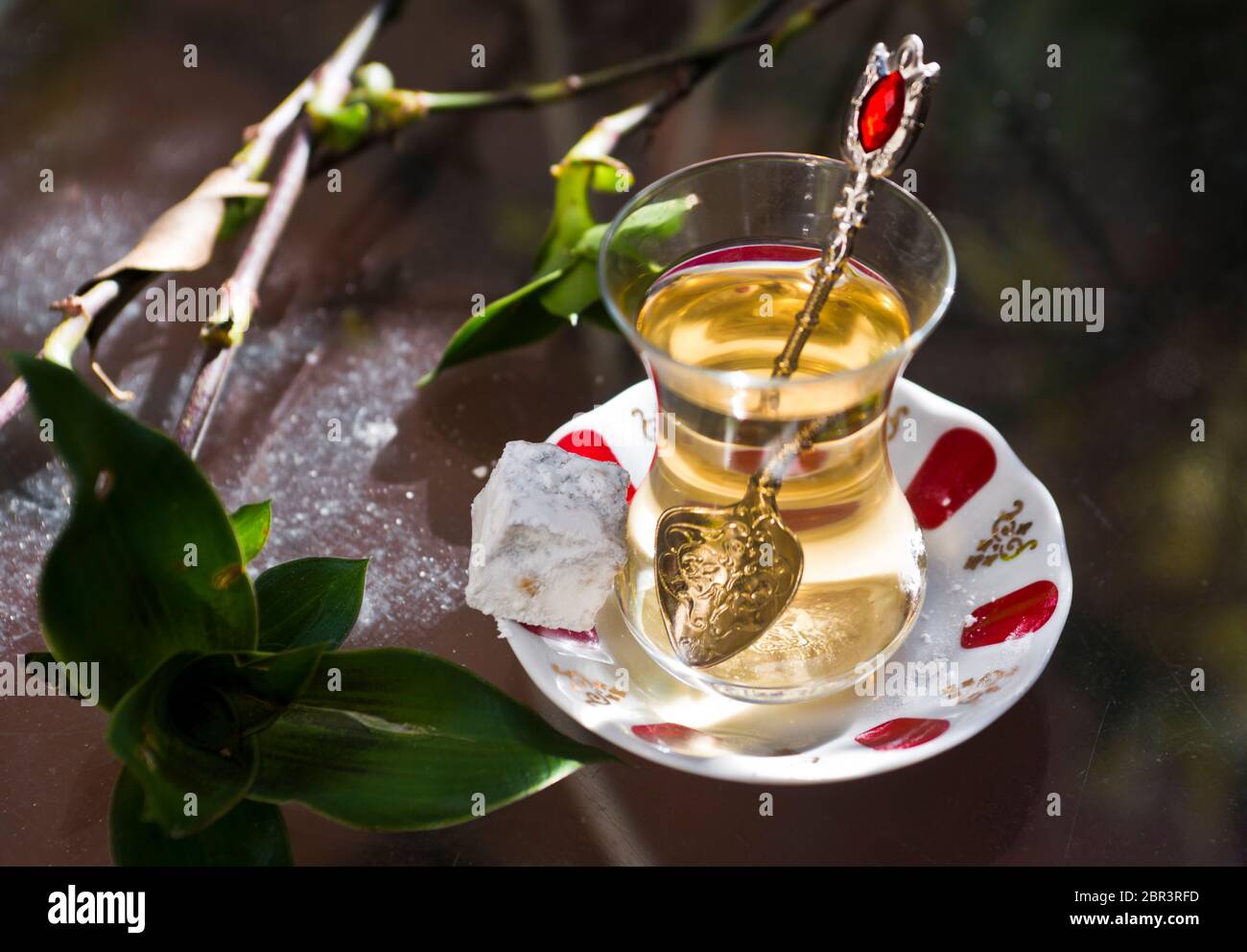 Türkischer Apfeltee und süßes (türkisches) Gebäck, serviert auf einem Glastisch im Garten Stockfoto