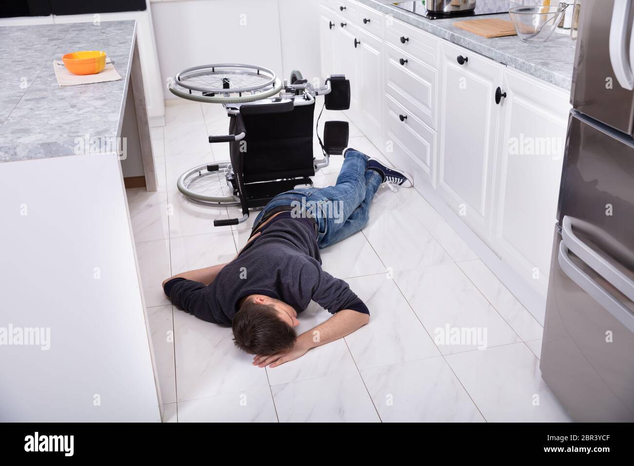 Behinderte Menschen liegen in der Küche nach Gefallen vom Rollstuhl Stockfoto