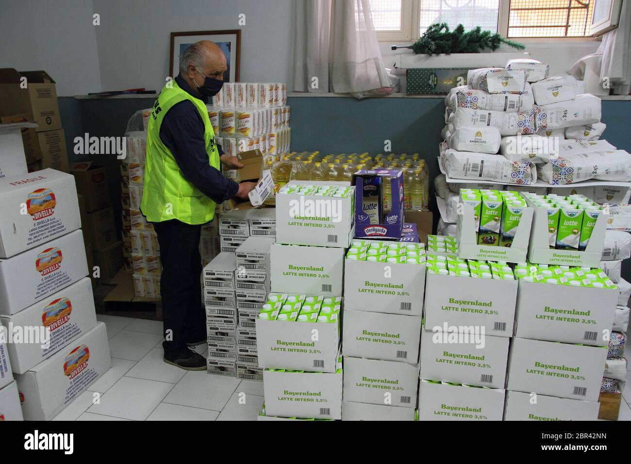 Ein Freiwilliger im Lager der Pfarrei caritas öffnet Pakete von getrockneten Hülsenfrüchten an Familien, die Nahrungsmittelhilfe benötigen verteilt werden Stockfoto