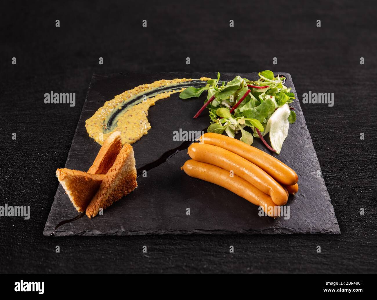 Frankfurter Würstchen serviert auf schwarzem Schiefer Stockfoto