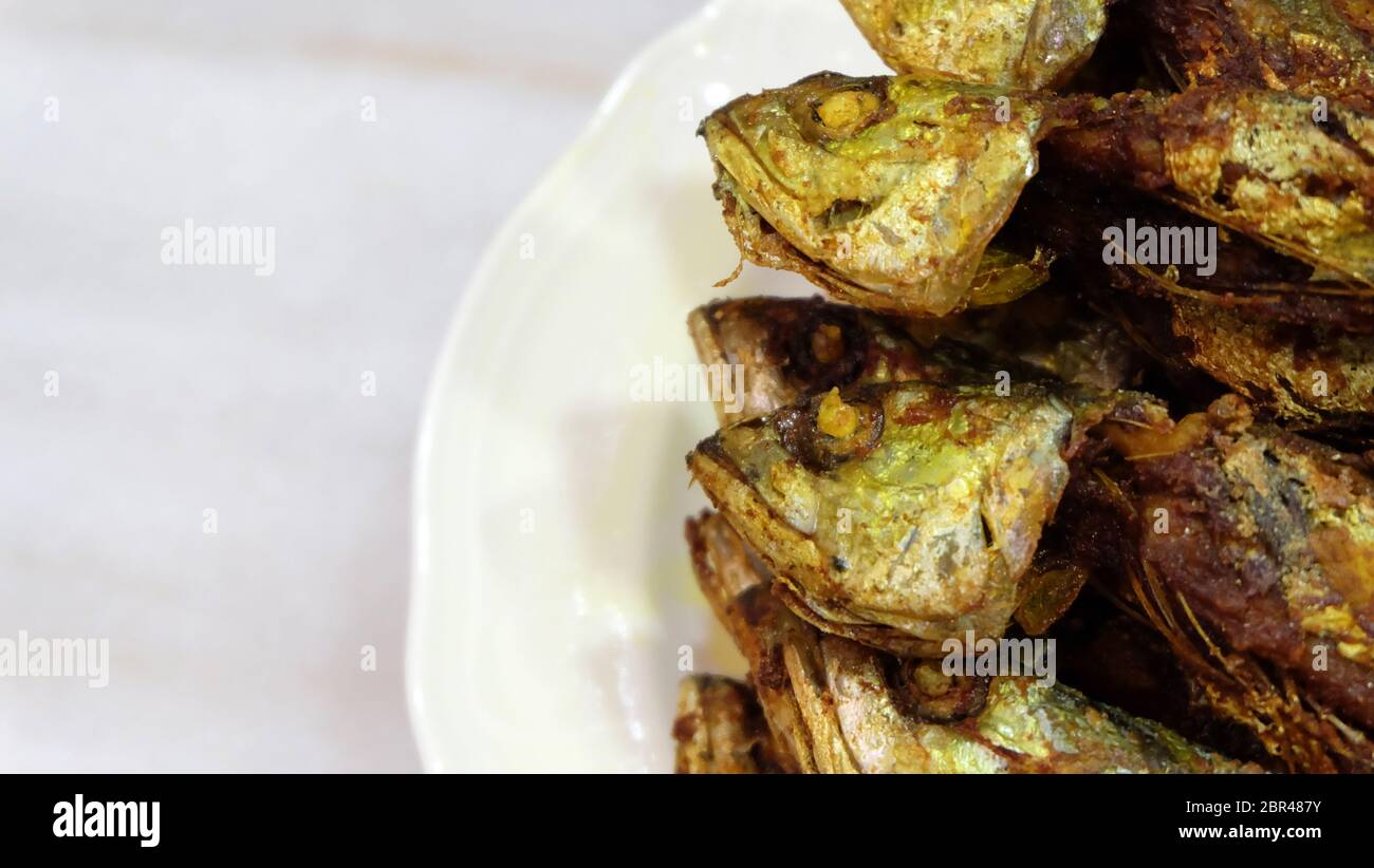 Nahaufnahme von Scrimp Scad Fisch, gebraten und serviert auf einem Teller, mit Marmorhintergrund. Stockfoto