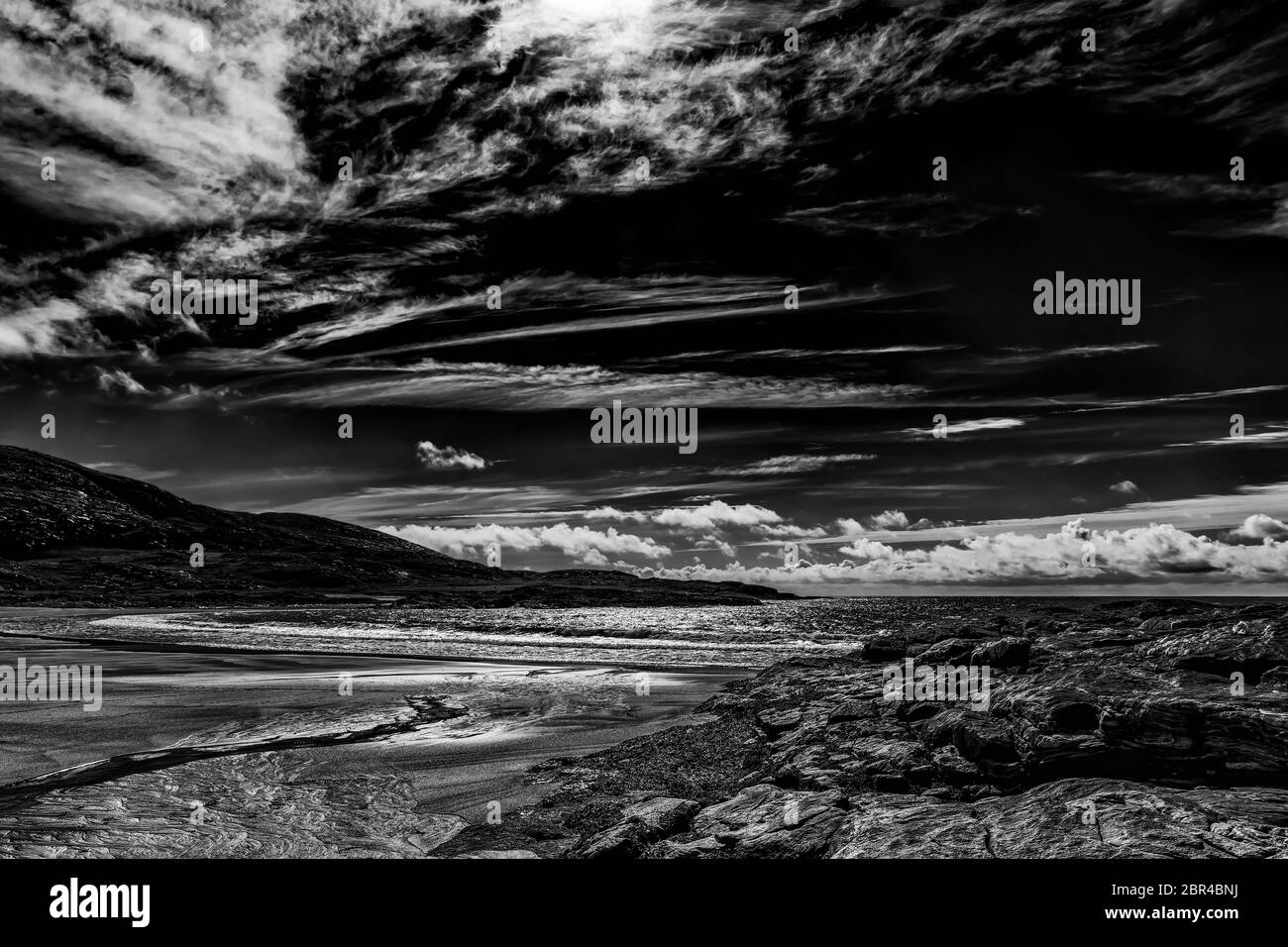 Kleine Bäche und Sandstrand, der bei Ebbe von Wellen geformt wird. Low-Key-Bild. Stockfoto