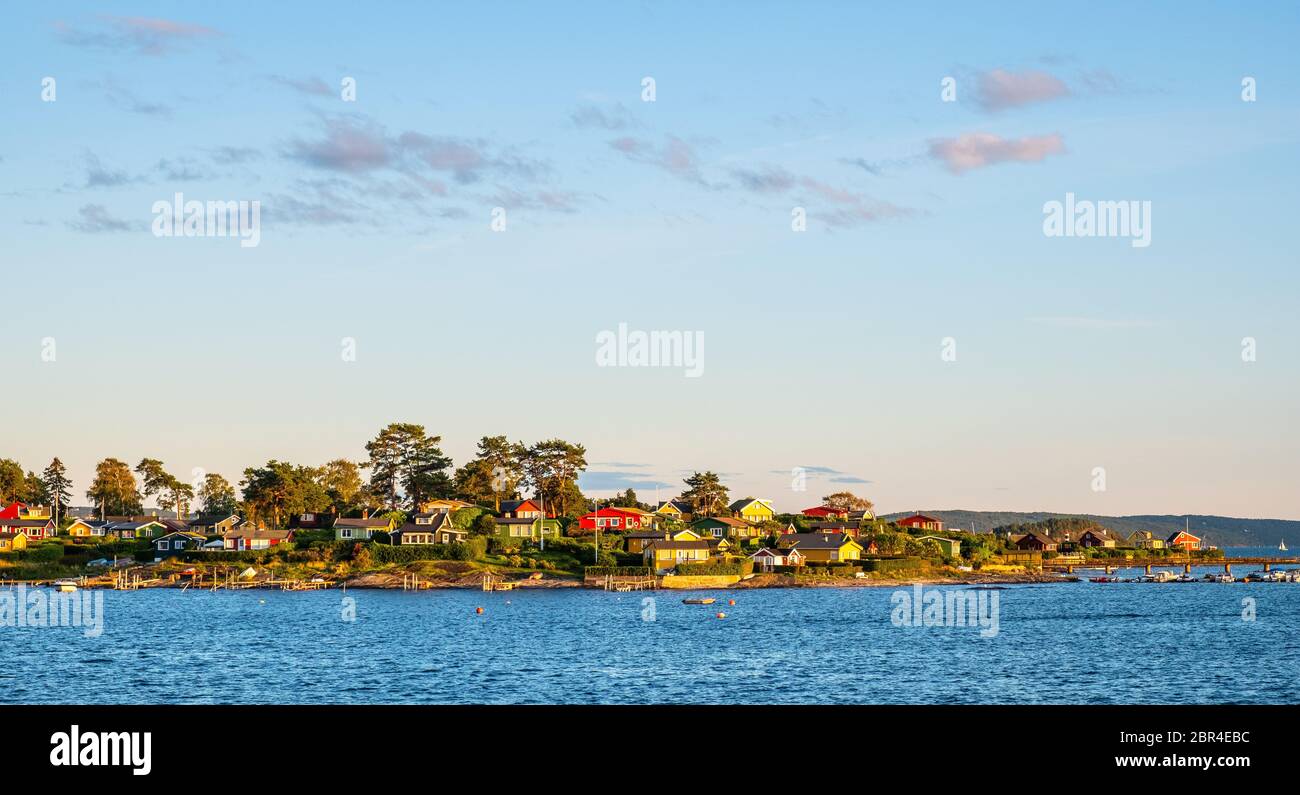 Oslo, Ostlandet / Norwegen - 2019/09/02: Panorama-Sonnenuntergang-Ansicht von Lindoya Insel am Oslofjord Hafen mit Sommerhäusern an der bewaldeten Küste Stockfoto