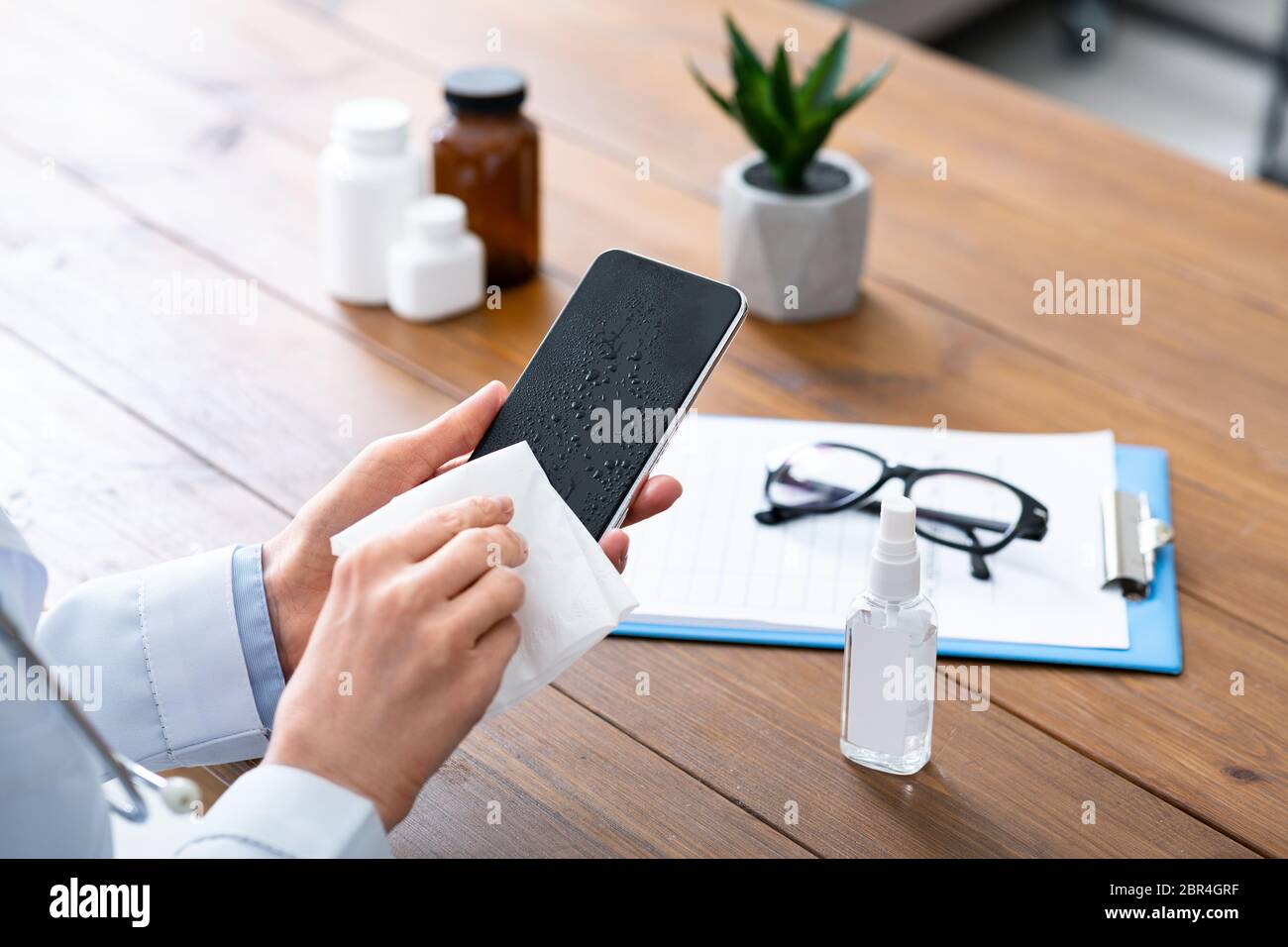 Smartphone-Desinfektion. Ärztin mit Desinfektionsmittel und Wischtücher, reinigt Telefon Stockfoto