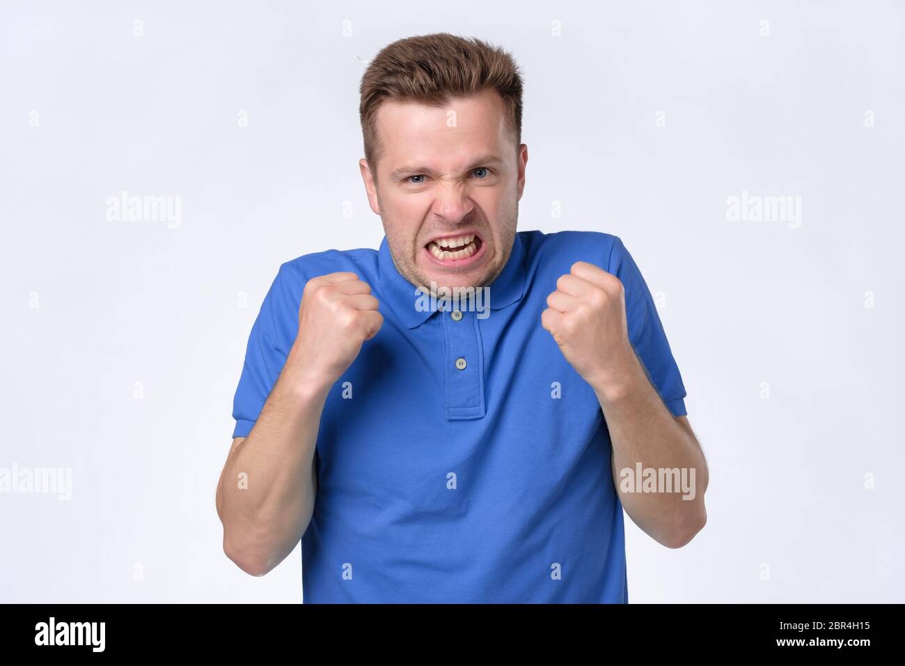 Verärgert junger Mann in blauem Hemd mit Fäusten bis schreien. Negative menschliche Emotion, Gesichtsausdruck. Nahaufnahme Stockfoto