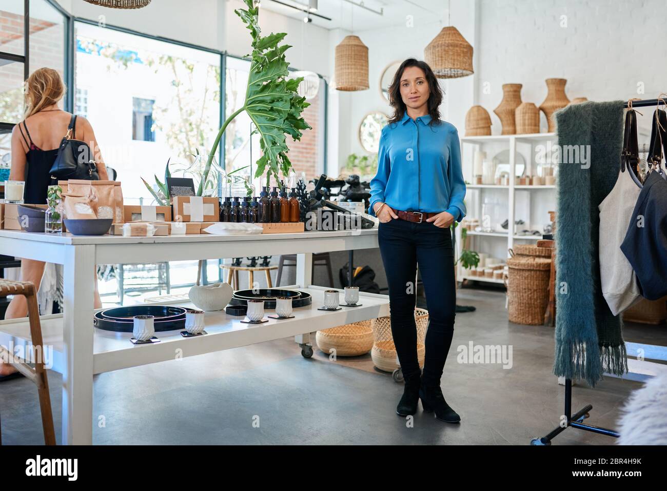 Junge asiatische Unternehmerin steht an einem Tisch in ihrem Geschäft Stockfoto