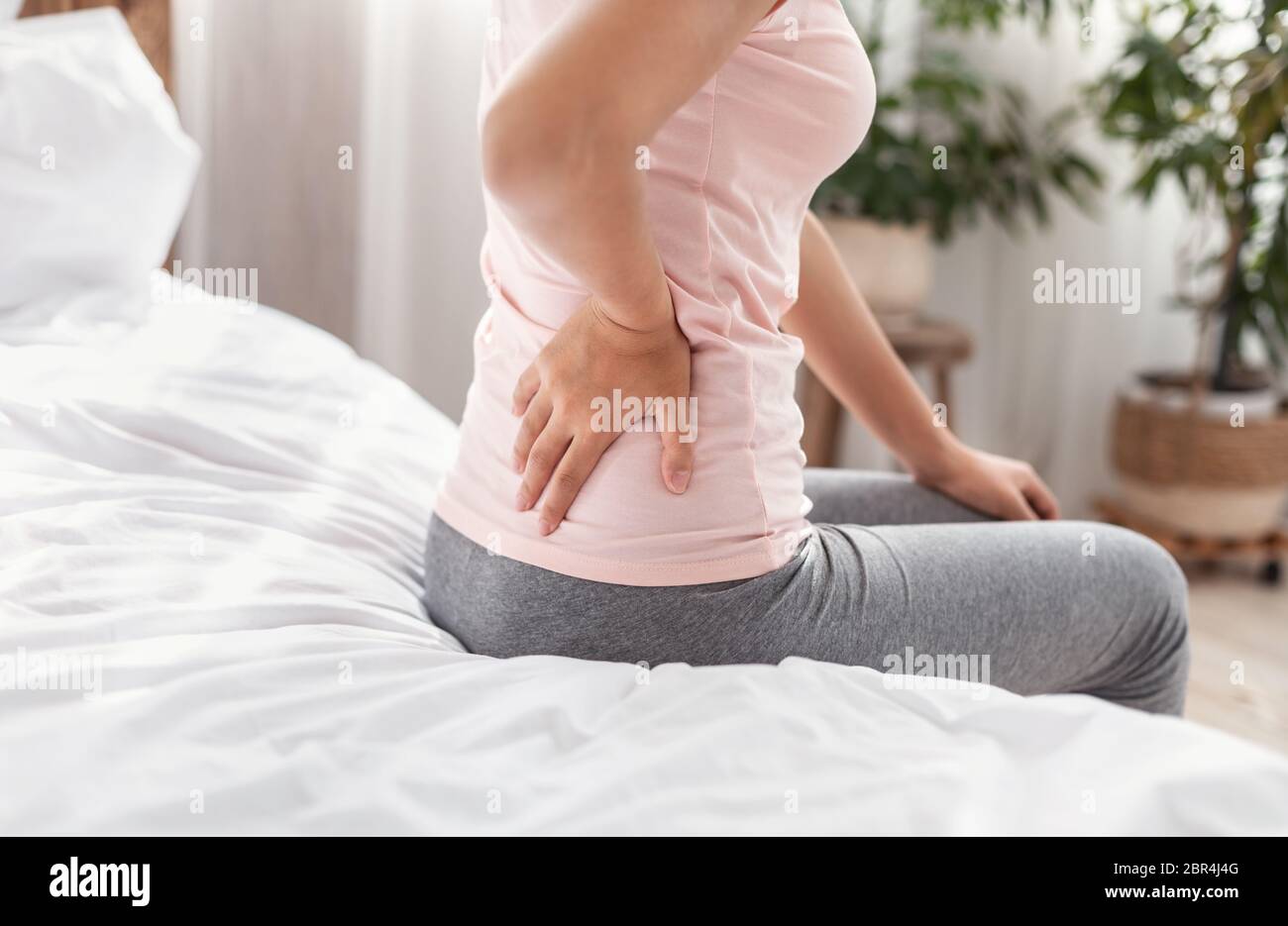 Unerkennbare Dame Berührt Rücken Leiden Schmerzen Auf Dem Bett Sitzen Stockfoto