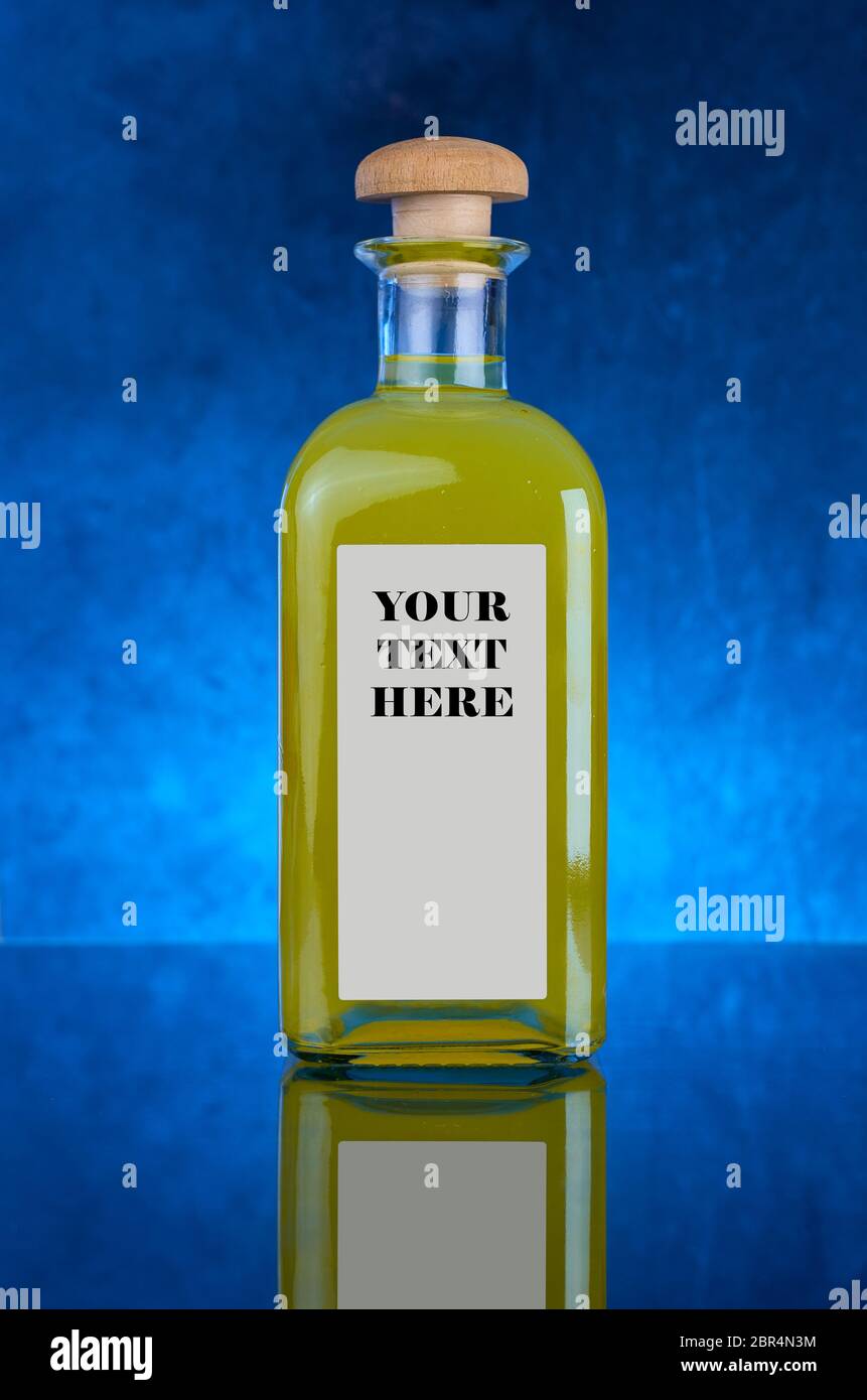 GELBE SPIRITUOSENFLASCHE UND -AUFNAHMEN, MIT BLAUEM HINTERGRUND UND ETIKETT MIT COPYSPACE IN JPG Stockfoto