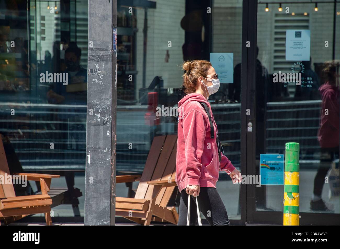 Montreal, CA - 20. Mai 2020: Frau mit Gesichtsmaske zum Schutz vor COVID-19 zu Fuß die Straße hinunter Stockfoto