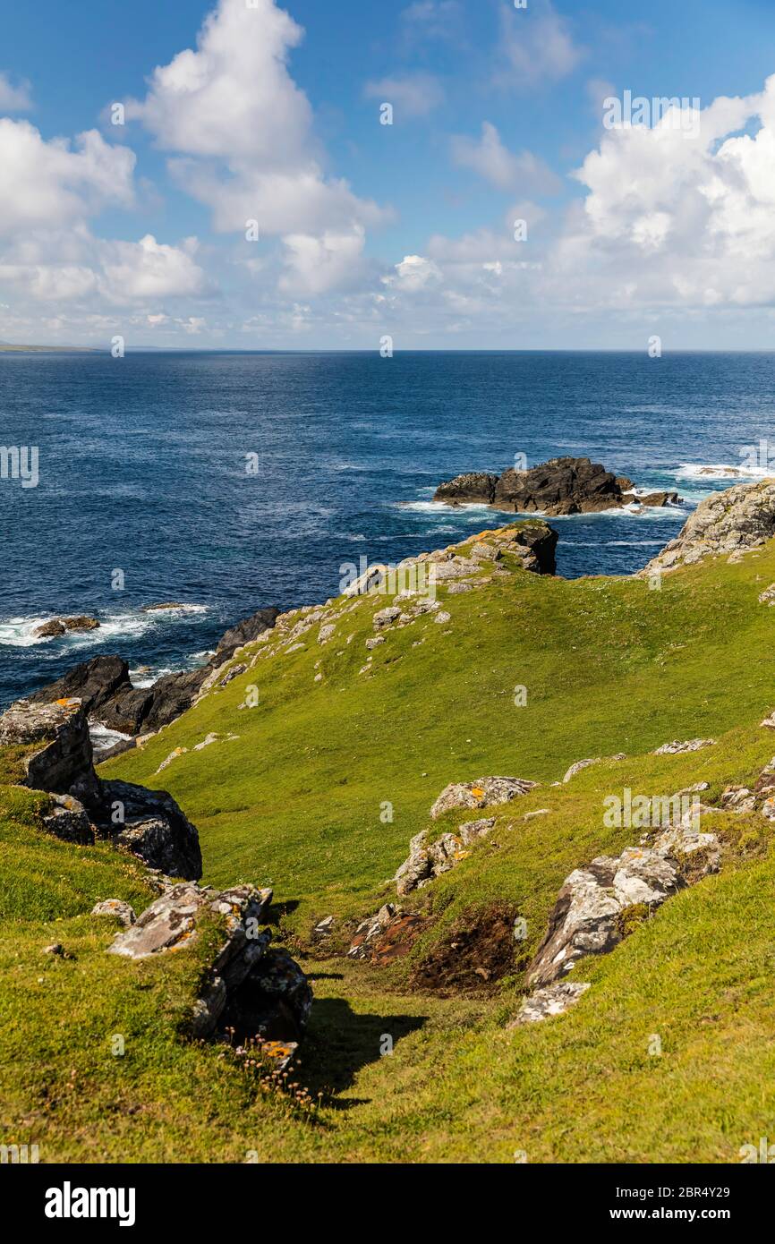 Auf dem Weg zum Meer finden Sie an einem sonnigen Tag grüne Felsen und Klippen an Schottlands Küste. Stockfoto