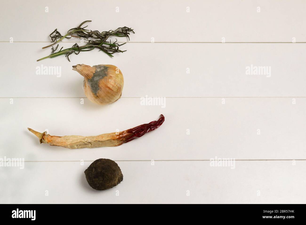 Faule Zwiebeln und rote Paprika, getrocknete Rosmarinzweige und Rüben. Konzept für Lebensmittelabfälle. Stockfoto