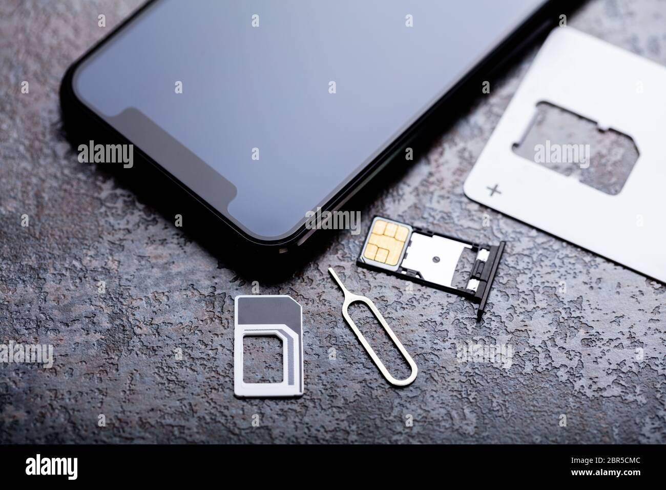 Handy in der Nähe von Nano-SIM-Karte in den Card Adapter mit Eject Pin über konkreten Hintergrund Stockfoto