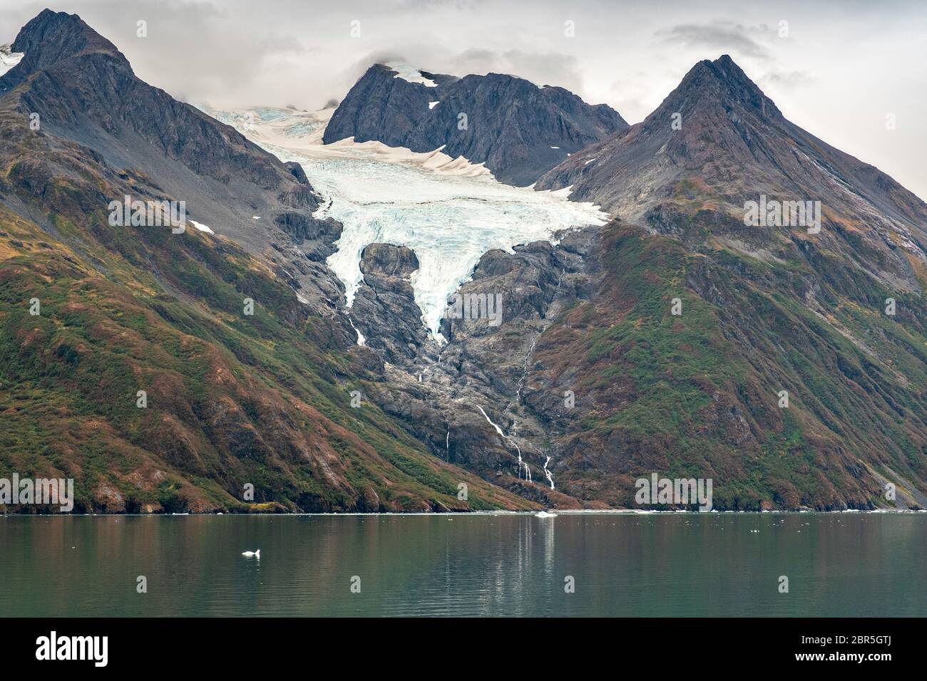 Schmelzwasser stürzt vom Serpentine Glacier in Barry Arm im Harriman Fjord, nahe Whittier, Alaska, auf den Mount Gilbert ab. Der Gletscher hat sich dramatisch von einem Leckerbisse zum hängenden Gletscher zurückgebildet. Stockfoto