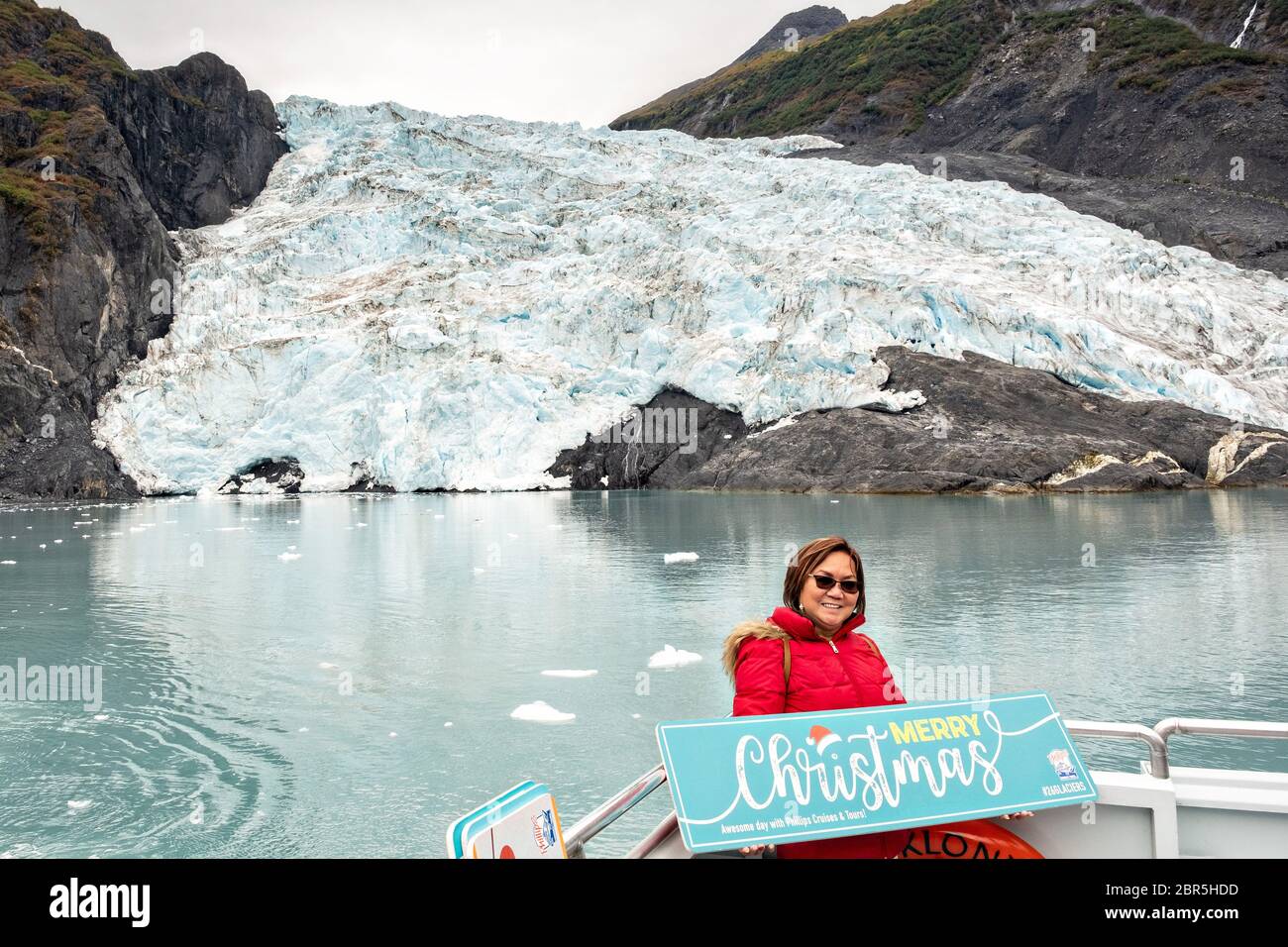 Ein philippinischer Tourist posiert vor dem Coxe Glacier, einem Leckerbisse in Barry Arm, Harriman Fjord, Prince William Sound in der Nähe von Whittier, Alaska. Stockfoto