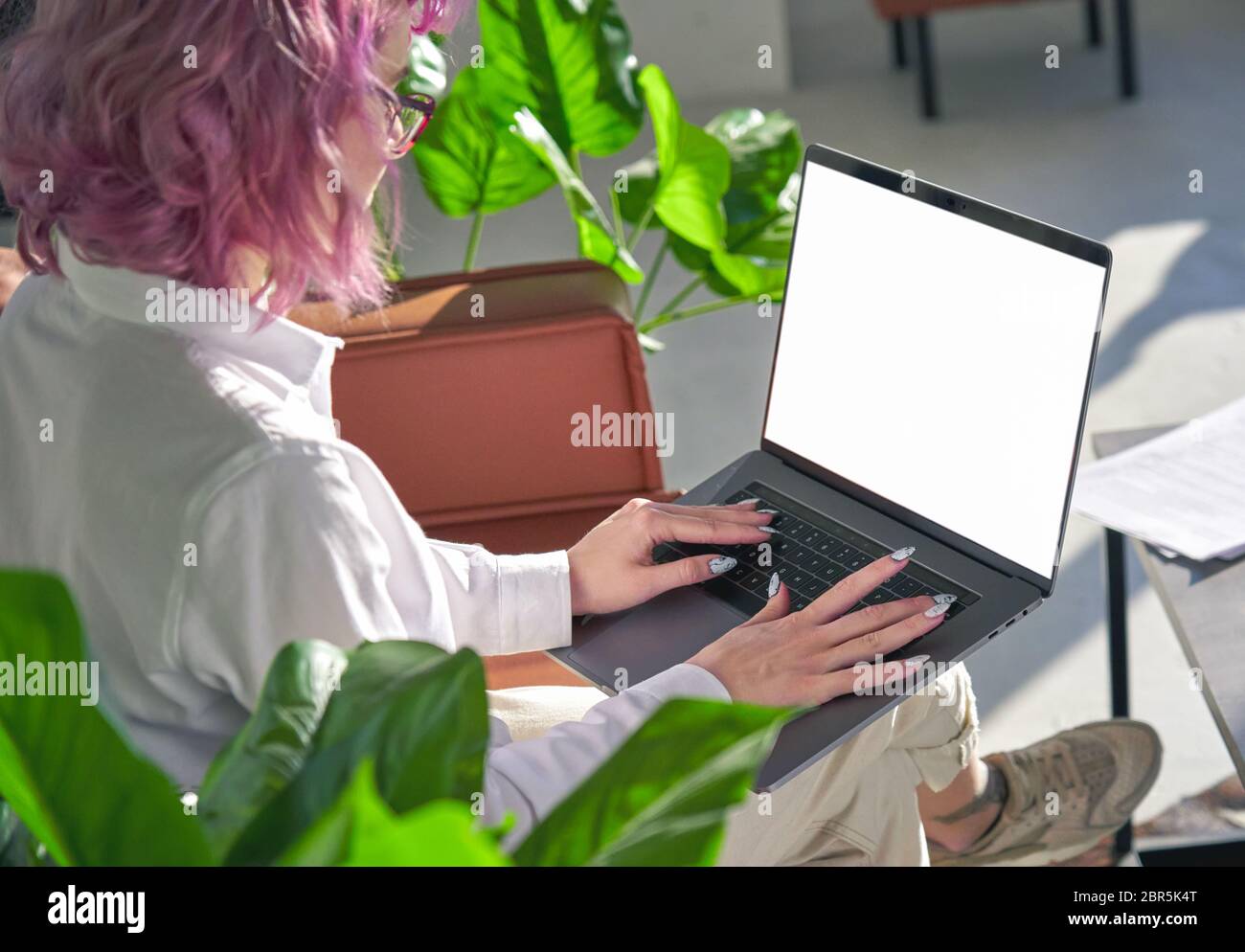 Junge Hipster Frau arbeiten online mit Laptop Mock-up-Bildschirm. Über der Schulter Stockfoto