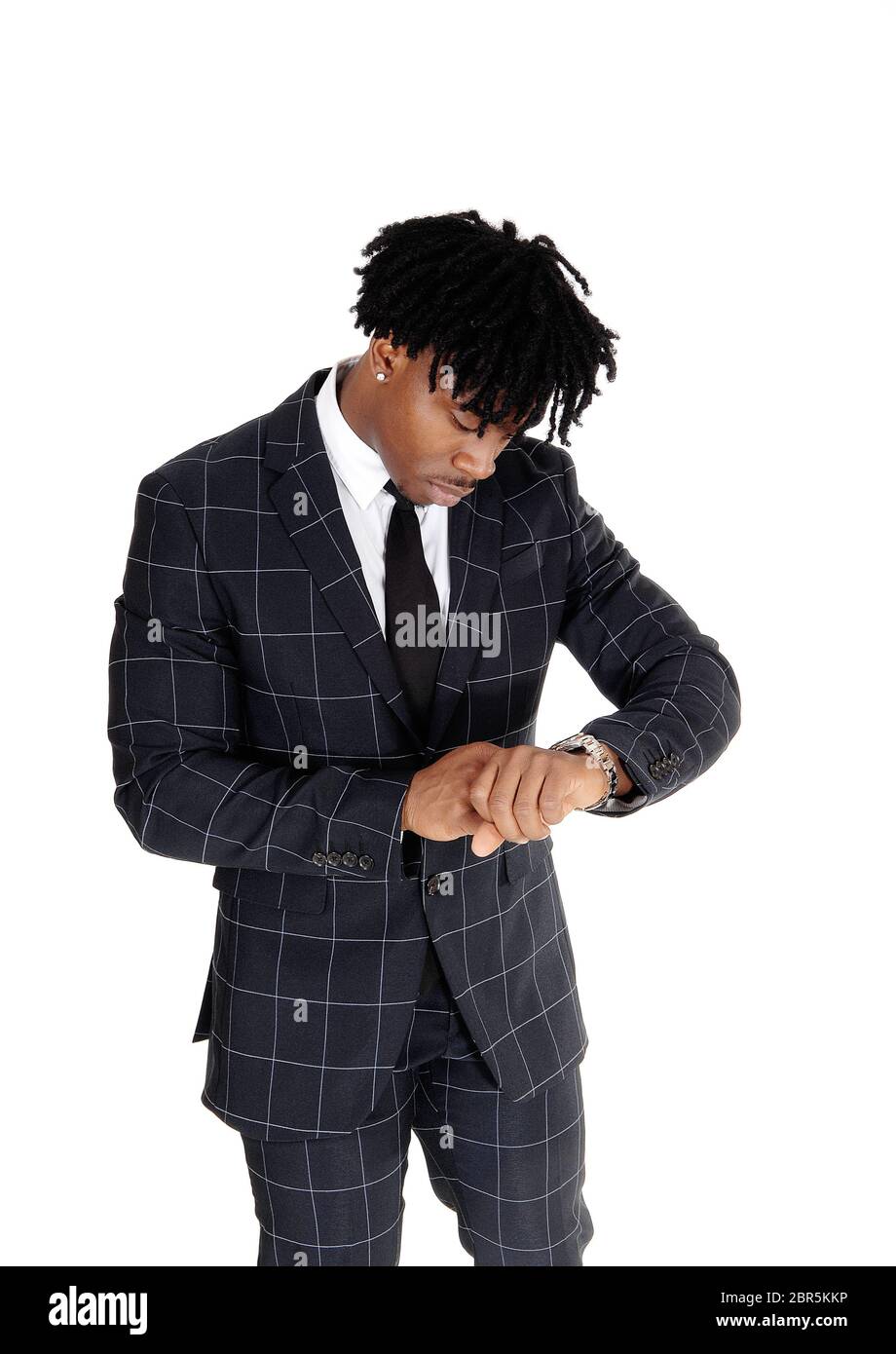Ein Afroamerikanischer junge Mann in einem dunklen Anzug und weißes Hemd und Krawatte, zu der Zeit auf seine Armbanduhr suchen, auf weißem Hintergrund Stockfoto