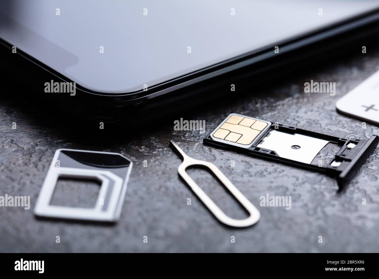 Handy in der Nähe von Nano-SIM-Karte in den Card Adapter mit Eject Pin über konkreten Hintergrund Stockfoto