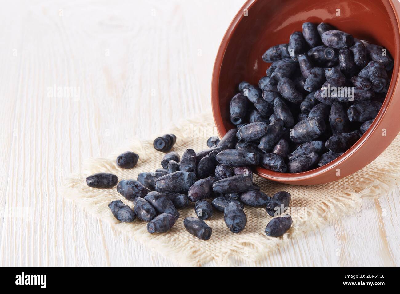 Geißblatt Beeren in einer Keramikschale auf Holzhintergrund. Stockfoto