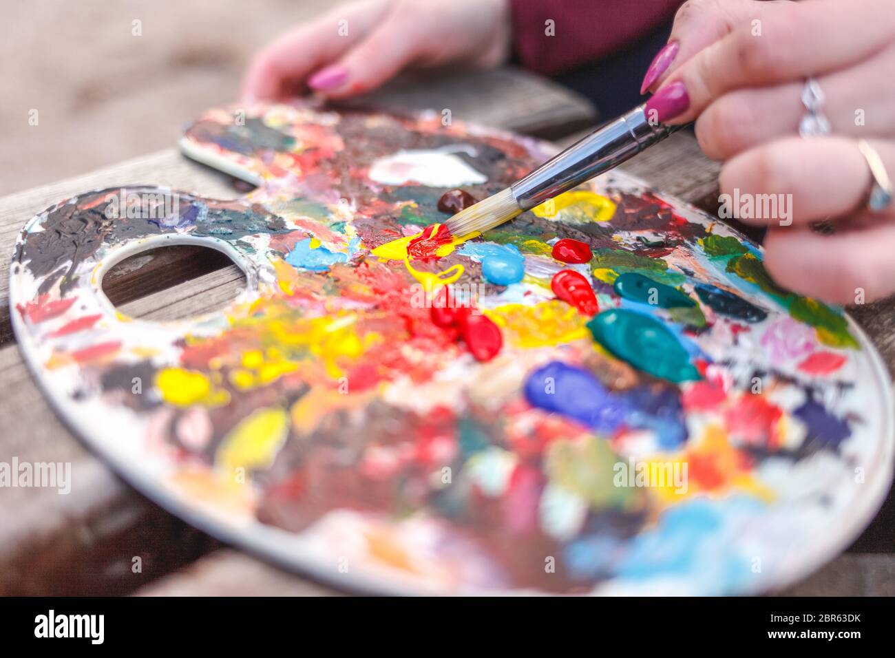 Der Künstler, der ein Bild im Park malt, mischt die Farben auf einer Palette Stockfoto