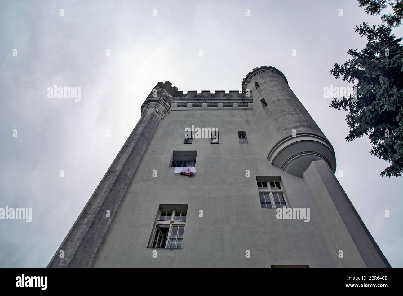 Alter Turm mit Zimmern. Aus einem Raum wird ein Vorhang aus dem Fenster gezogen. Stockfoto