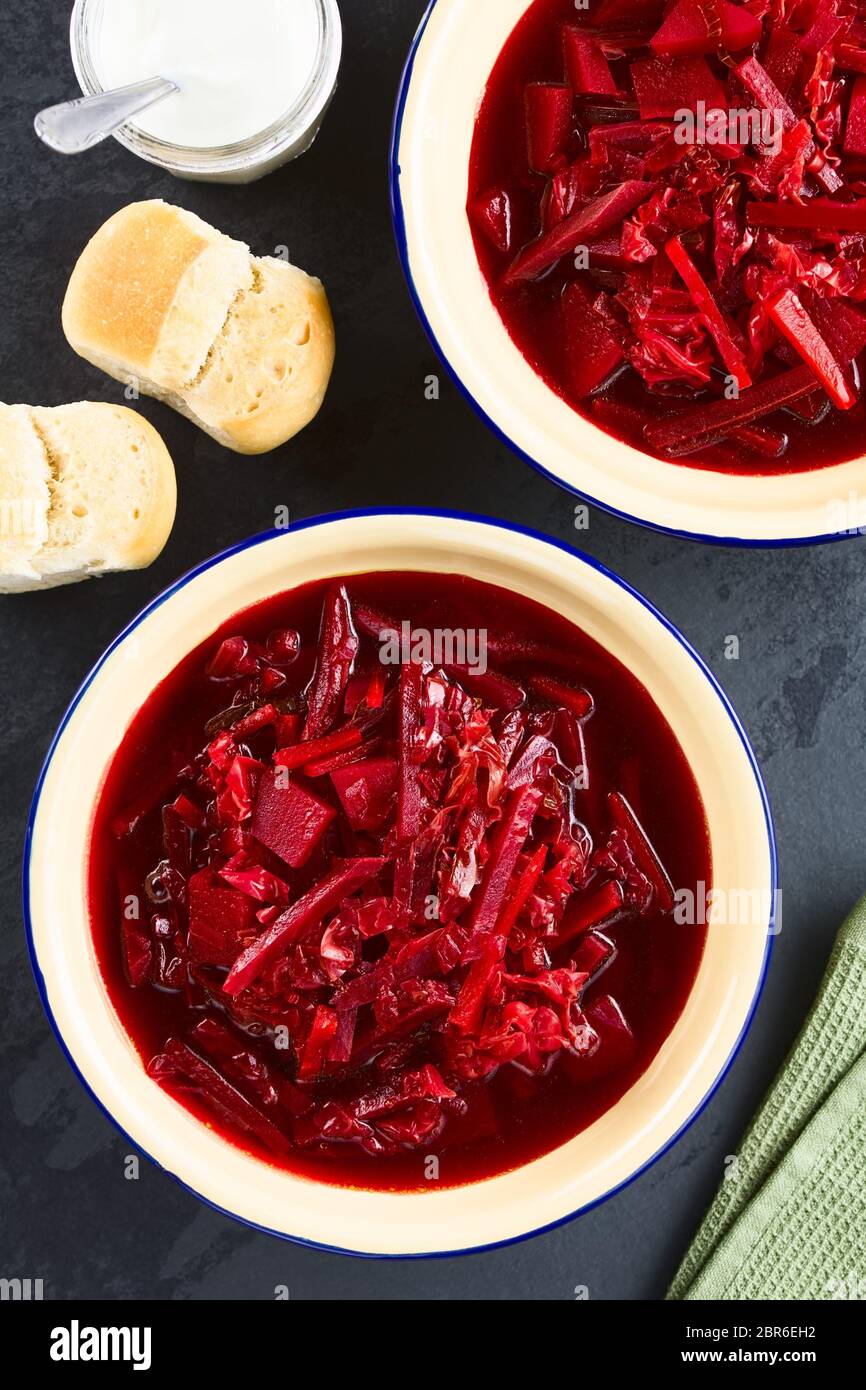 Frisch hausgemachter vegetarischer Borscht, eine traditionelle osteuropäische Suppe aus Rote Bete, Karotte, Kohl, Kartoffeln, Zwiebeln und Tomaten, serviert im Emaille b Stockfoto