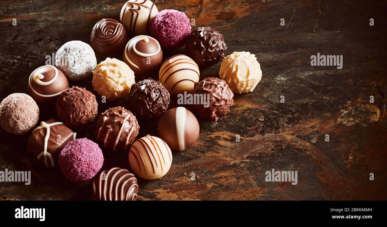 Luxus handgemachte Schokolade Pralinen noch Leben in ein ordentliches Rechteck auf rustikalen oder Vintage Holz mit Kopie Raum in Banner Format angeordnet Stockfoto