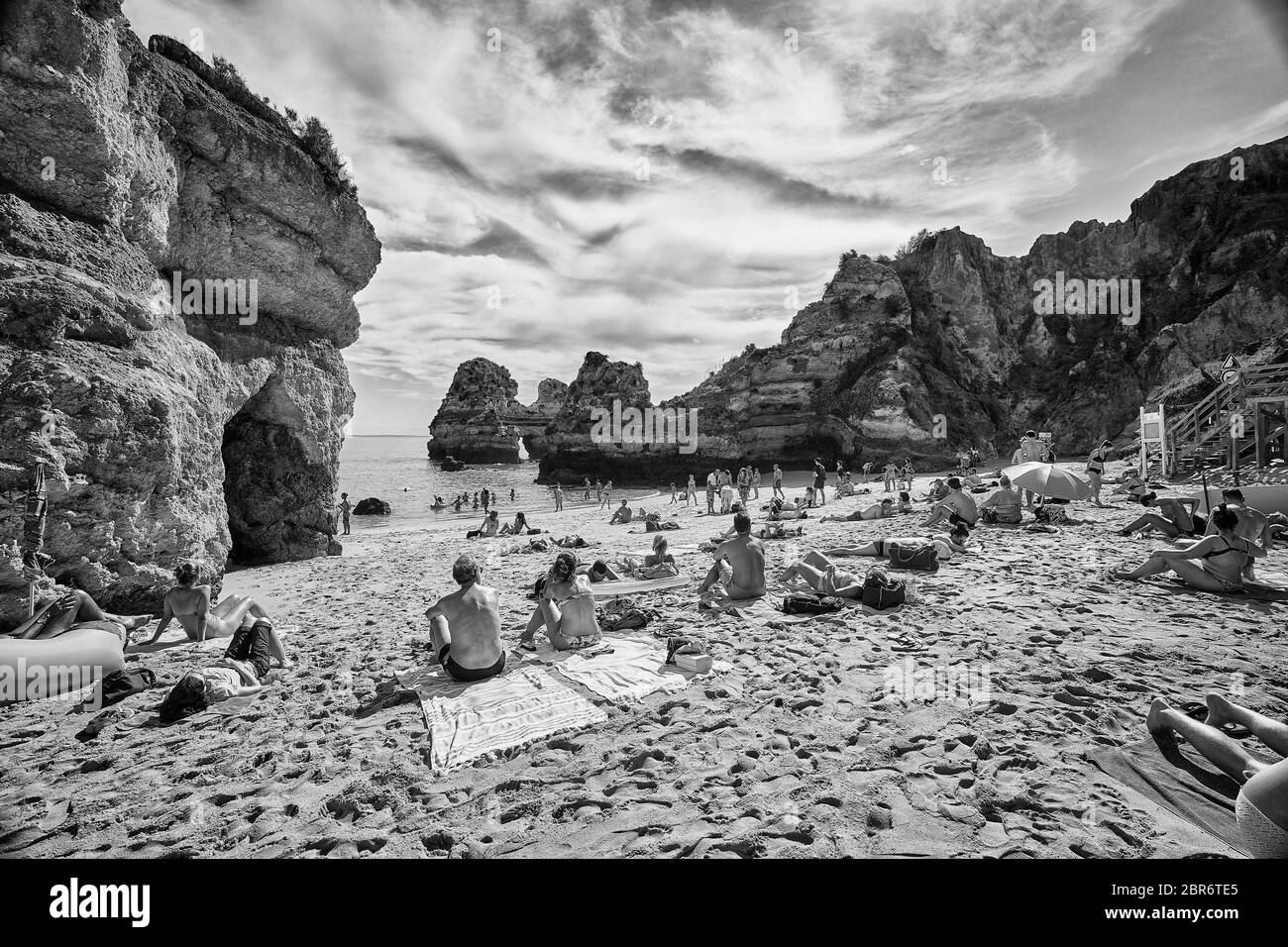 Die Menschen entspannen sich an den Stränden von Lagos, Portugal, wo dramatische Sandsteinfelsen aus dem Wasser des Mittelmeers ragen Stockfoto