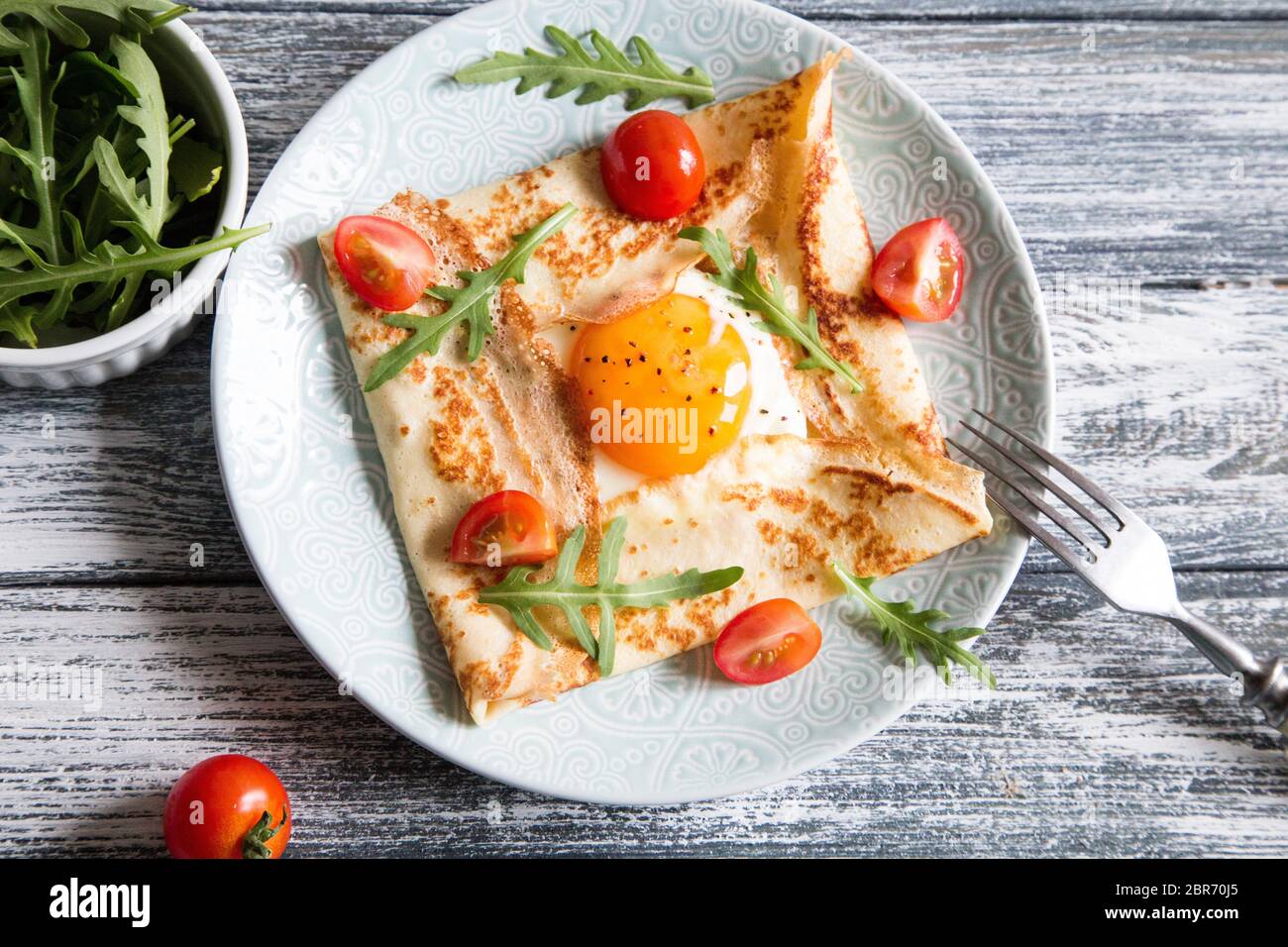 Crepes mit Eiern, Käse, Rucola Blätter und Tomaten. Galette abgeschlossen. Traditionelles Gericht galette Sarrasin Stockfoto