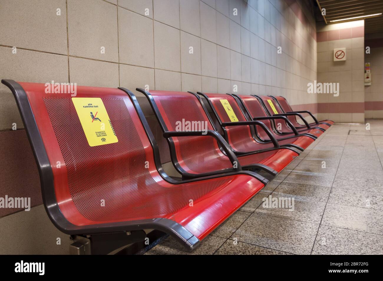 "Ich sitze nicht hier", heißt es in den Zeitungen auf den Stühlen der U-Bahn-Station Omonoia in Athen, da die Regierung die Passagiere auffordert, halbe Sitze zu benutzen Stockfoto