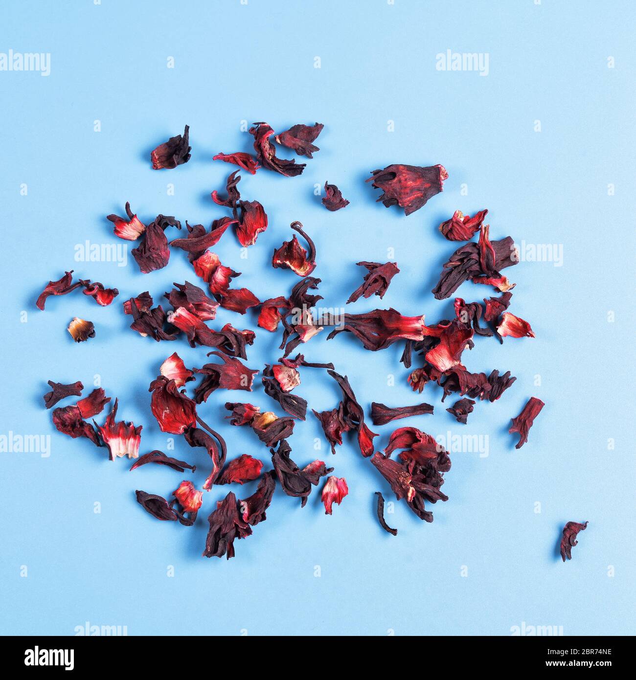 Haufen von trockenen Hibiskus Karkade Kräutertee auf blauem Hintergrund, Draufsicht. Stockfoto
