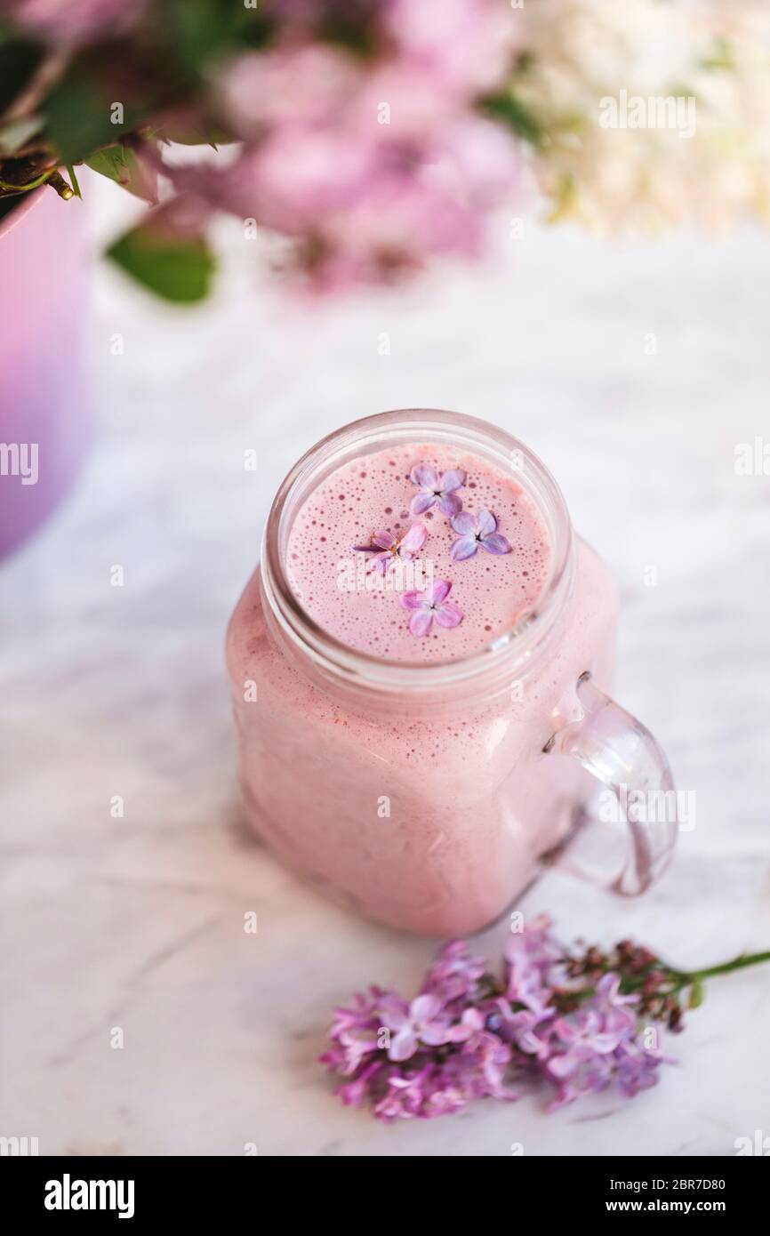 Erdbeer-Smoothie mit lila Blüten Stockfoto