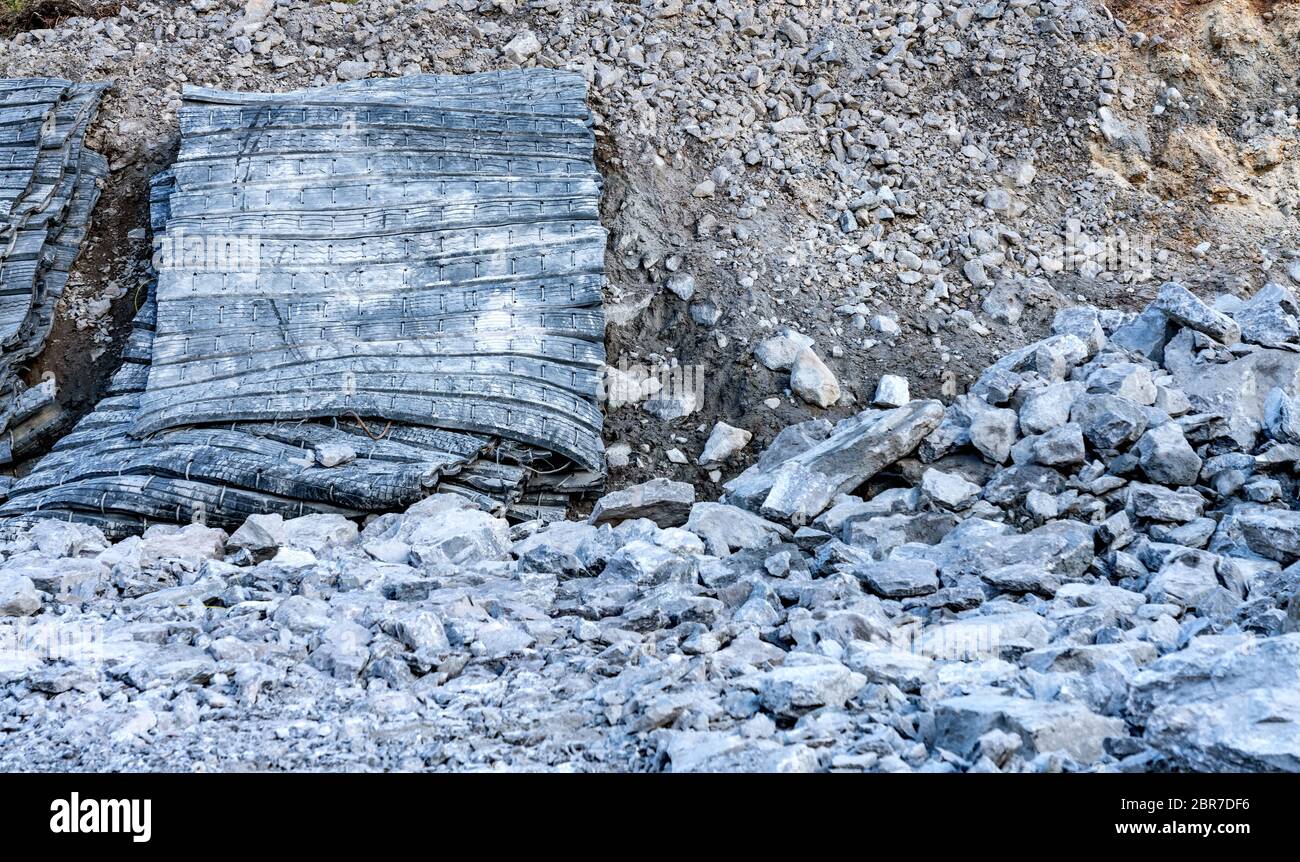 Nahaufnahme Foto Blast Schutz Gummimatten an der Seite des Bereichs mit vielen Steinen aus gestrahlten Felsen, neue Straße Baustelle. Sicherheitsausrüstung zu prote Stockfoto