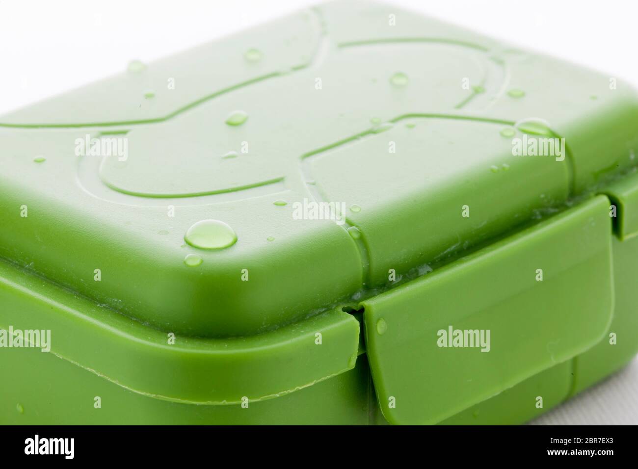 Nahaufnahme einer gebrauchten grünen Seifenbox mit Wassertropfen vor weißem Hintergrund. Stockfoto