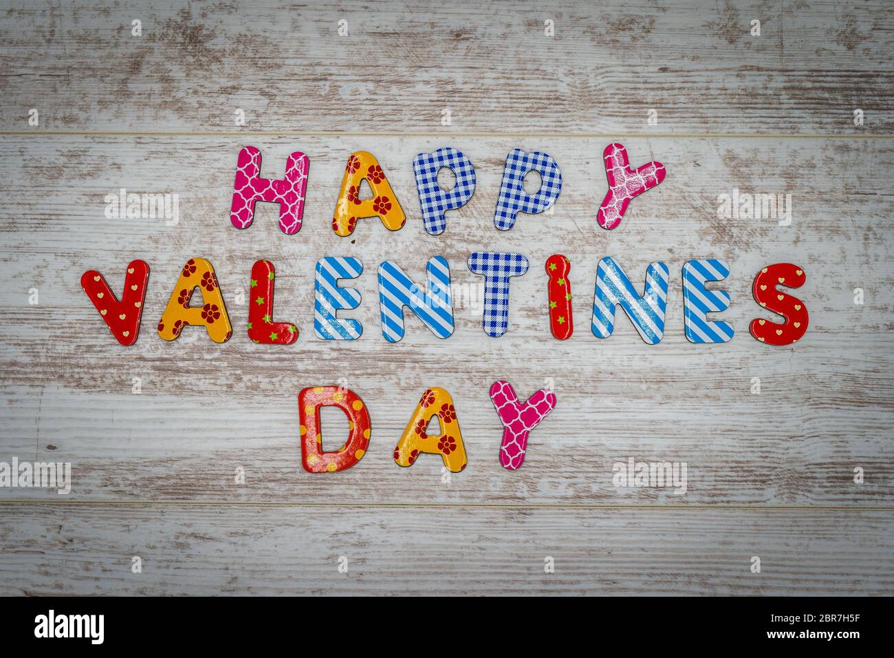Happy Valentines Day aus einzelnen bunten Buchstaben in Linien auf weiß bemalten Eichenholzplatten Stockfoto