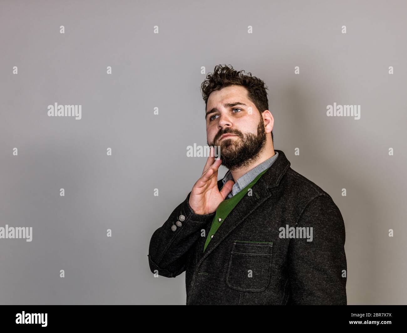 Cool Mann mit Tracht posiert vor grauem Hintergrund Stockfoto