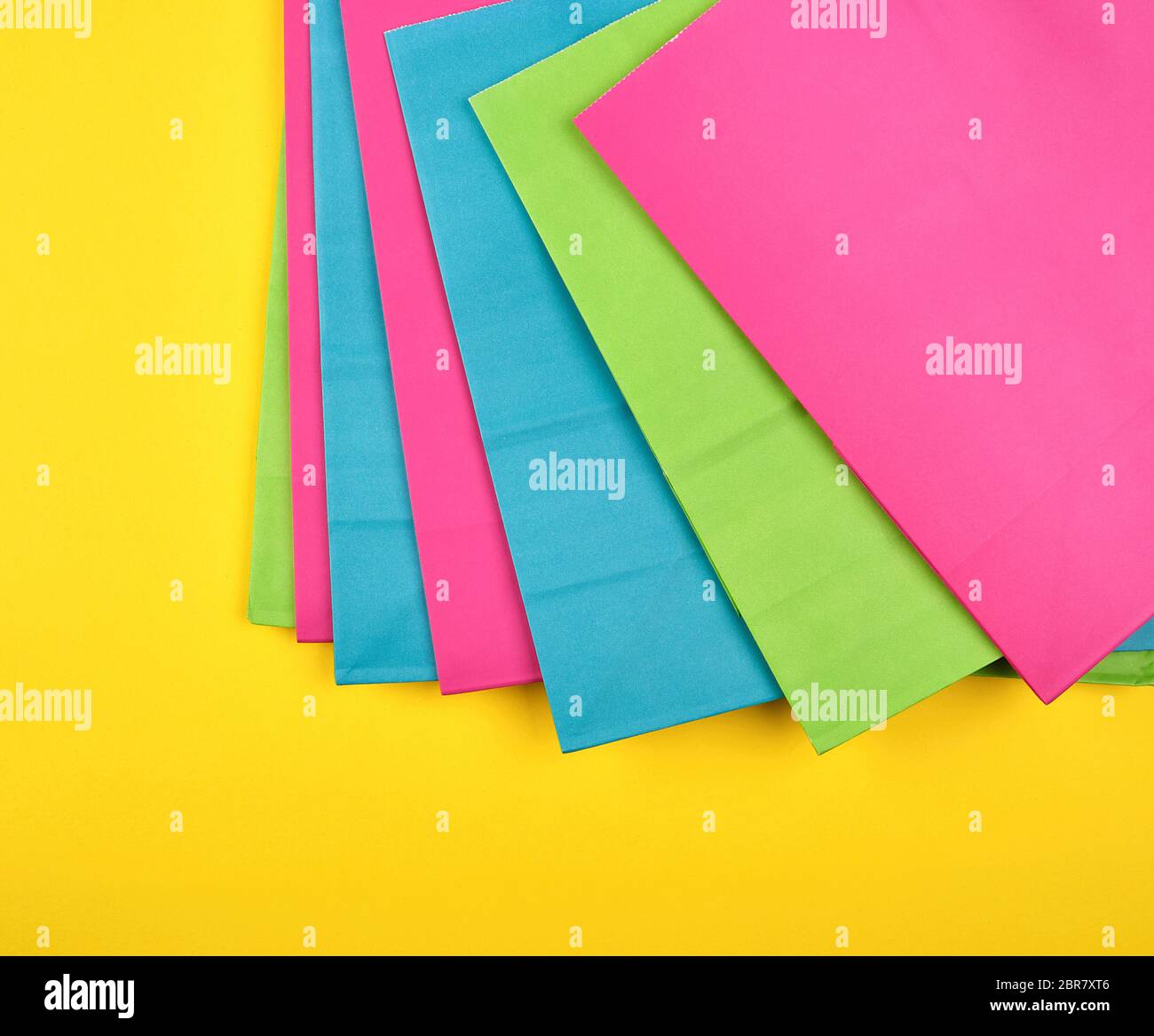 Multi-farbiges Papier Einkaufstüten auf gelbem Hintergrund, flach Stockfoto
