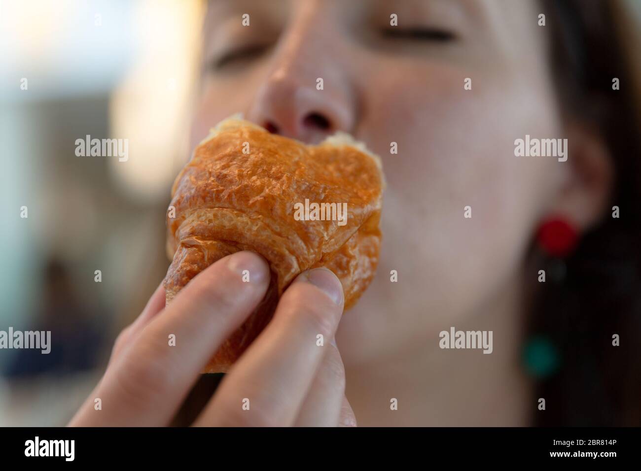 Junge Frau isst Croissant, Genuss, Schuld frei Essen Stockfoto
