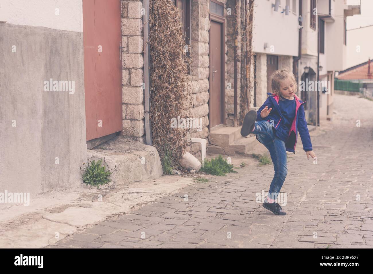 Kleines Mädchen Spaß üben Kicks auf einer Straße in Ohrid, Mazedonien Stockfoto