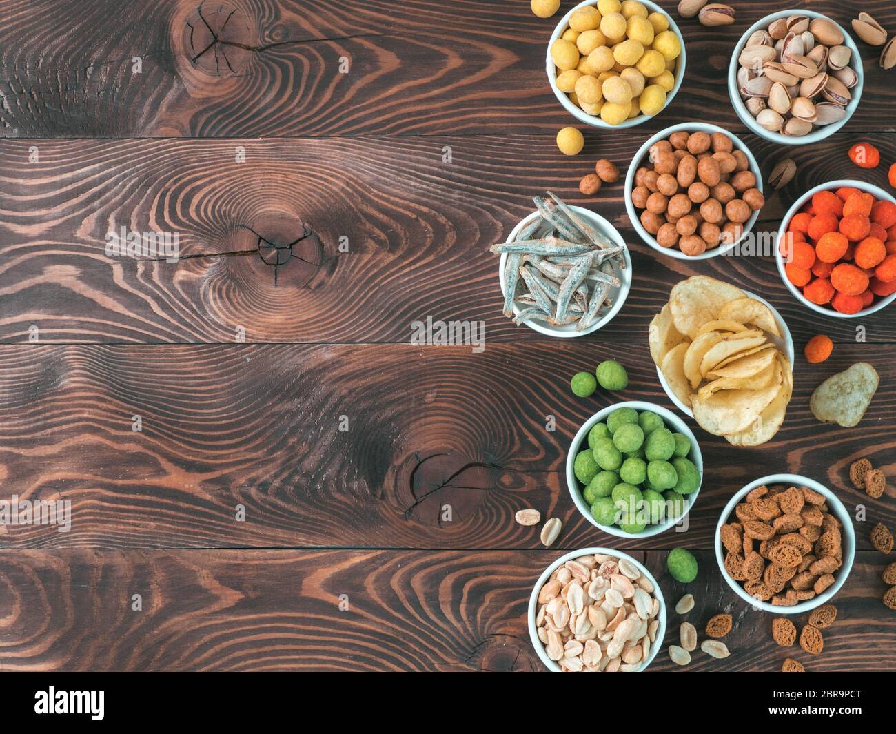 Sortiment von verschiedenen Snack für Bier, Wein, Party. Erdnüsse in Coconut Glasur, grüne vasabi, rote scharfe Chili, gelben Käse Glasur, Chips, Pistazie, Stockfoto