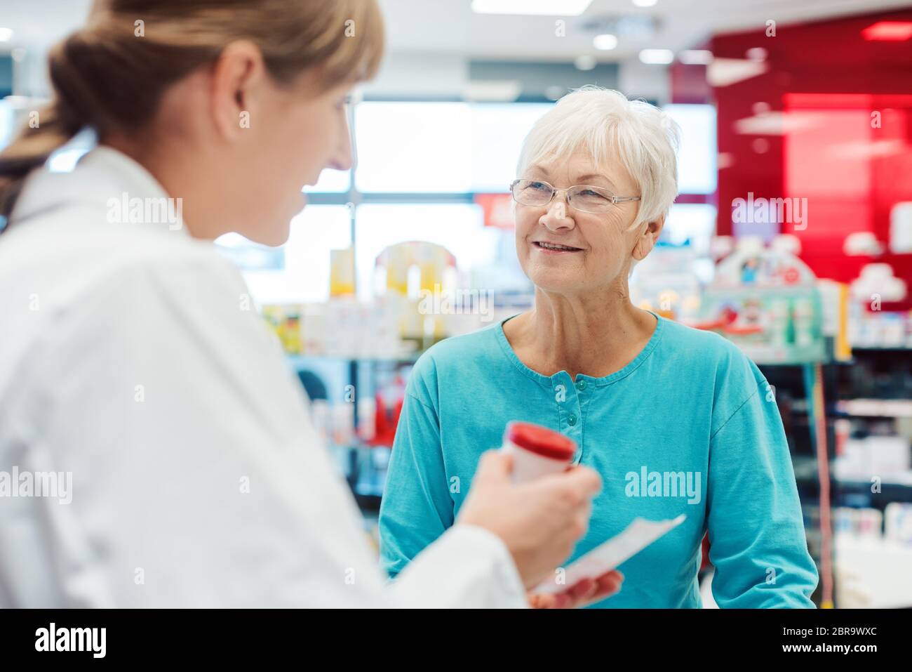 Ältere Frau in der Apotheke das Gespräch mit dem Chemiker oder Apotheker erklären Wirkungen einer Droge Stockfoto