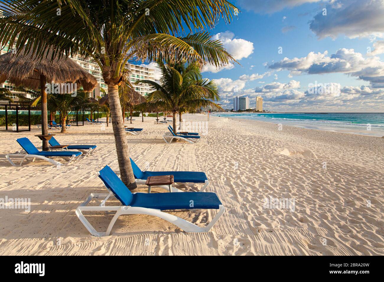 Liegestühle und Palmen am Strand in Cancun, Mexiko. Stockfoto