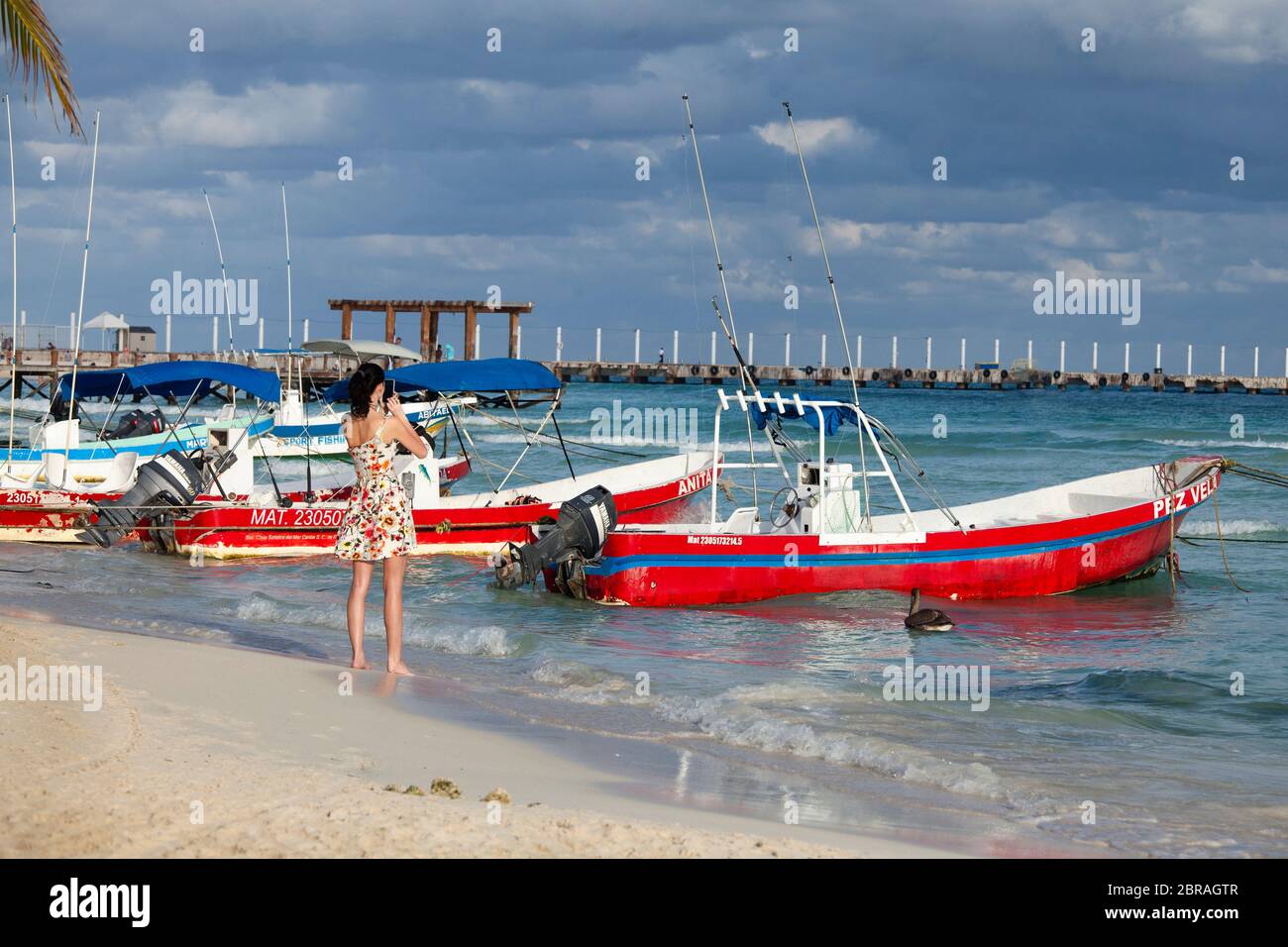 Eine junge Frau fotografiert bunte Boote in der Nähe der Docks von Playa del Carmen, Quintana Roo, Mexiko. Stockfoto