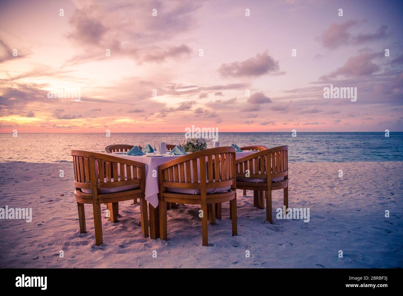 Sonnenuntergang stimmungsvolle Strandlandschaft in Luxus-Resort, Strand Abendessen. Dekorierter Tisch mit Abendessen am tropischen Strand. Stockfoto