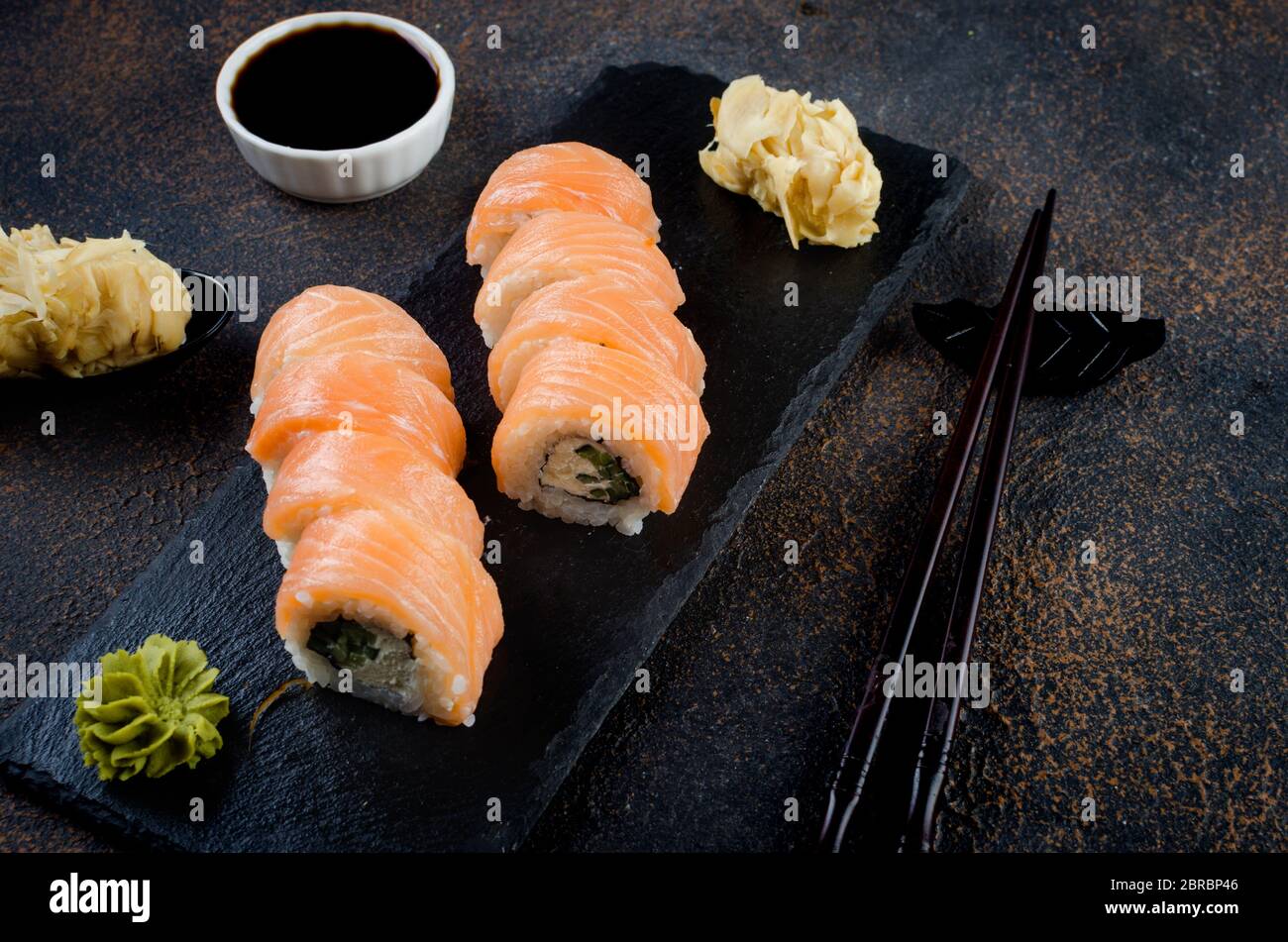 Philadelphia Roll Sushi mit Lachs und Frischkäse auf schwarzem Steinteller Stockfoto