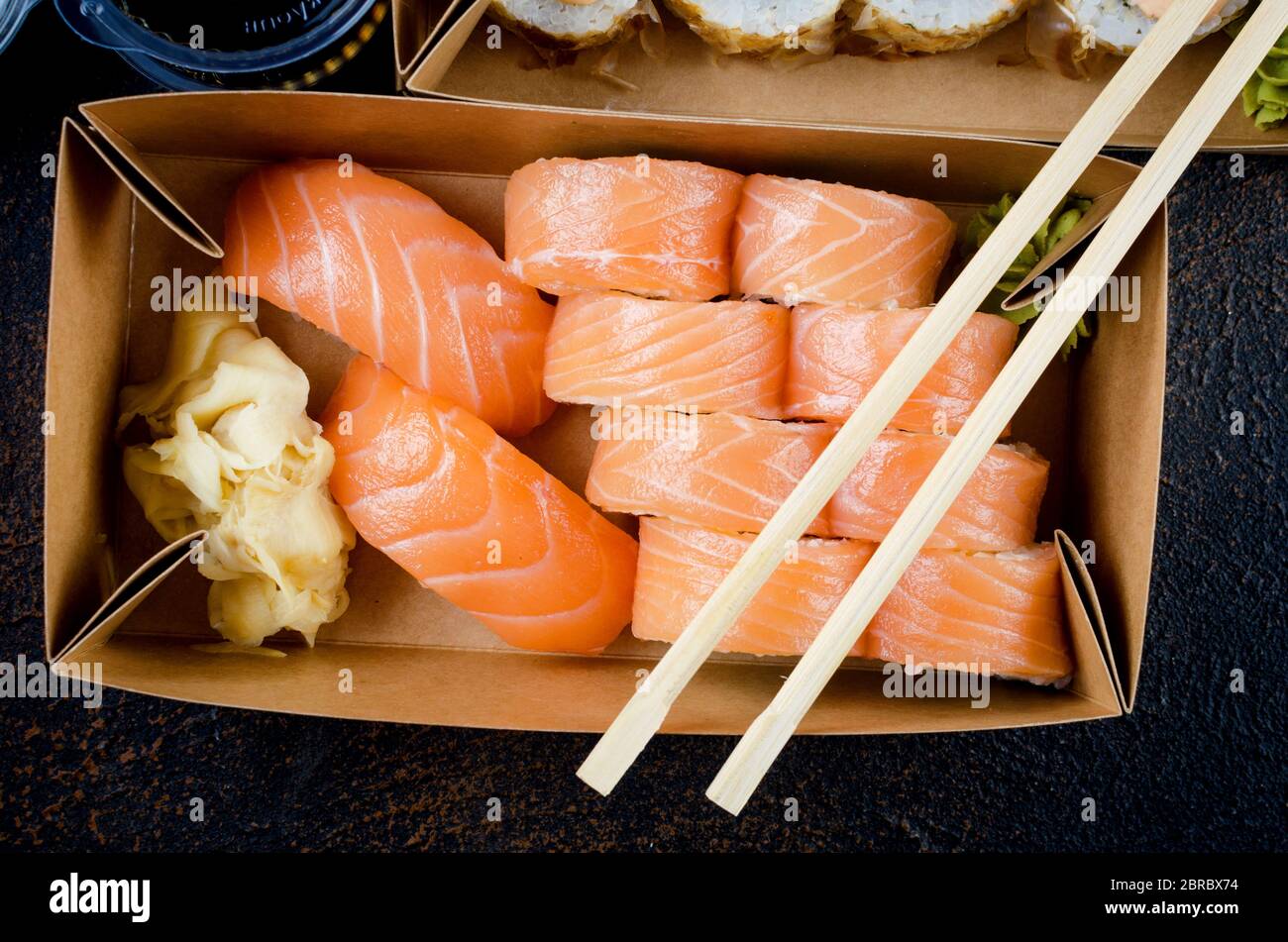 Leckere Sushi-Brötchen in Einweg-Kraftpapier-Boxen, Saucen, Essstäbchen. Sushi zum Mitnehmen oder Anliefern Stockfoto