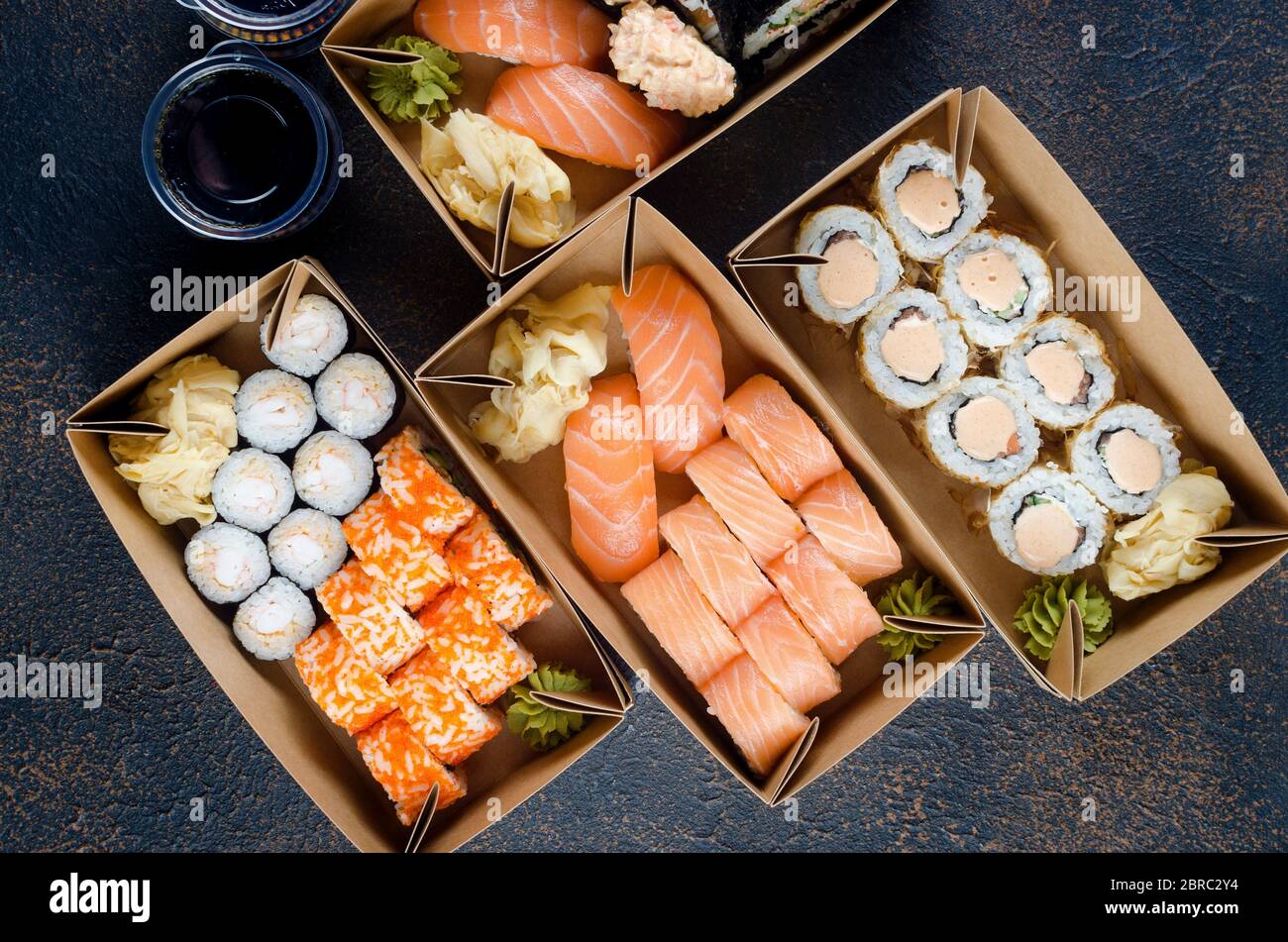Leckere Sushi-Brötchen in Einweg-Kraftpapier-Boxen, Saucen, Essstäbchen. Sushi zum Mitnehmen oder Anliefern Stockfoto